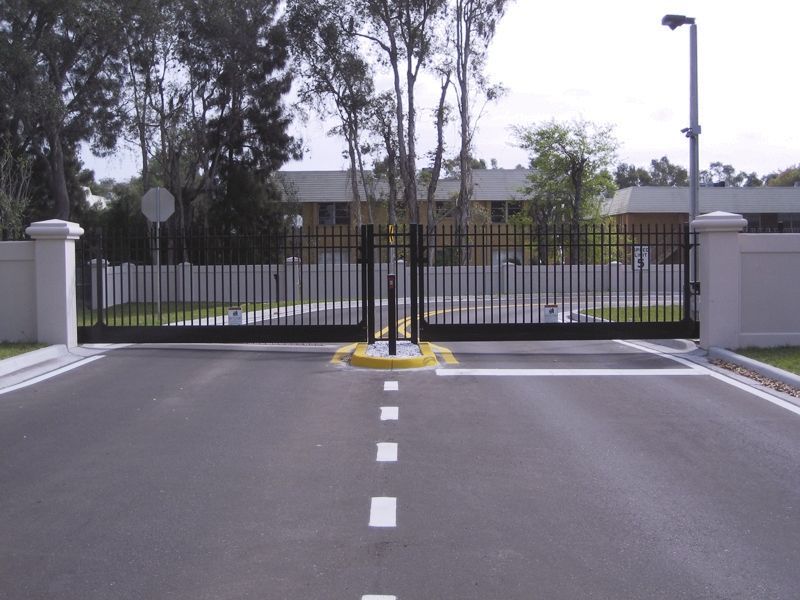 A gated entrance with a fence and trees in the background