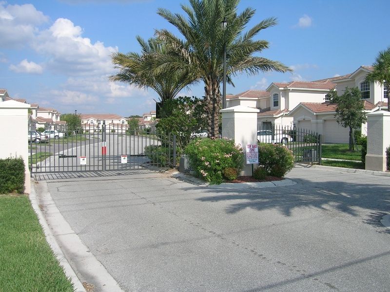 A gated entrance to a residential area with palm trees