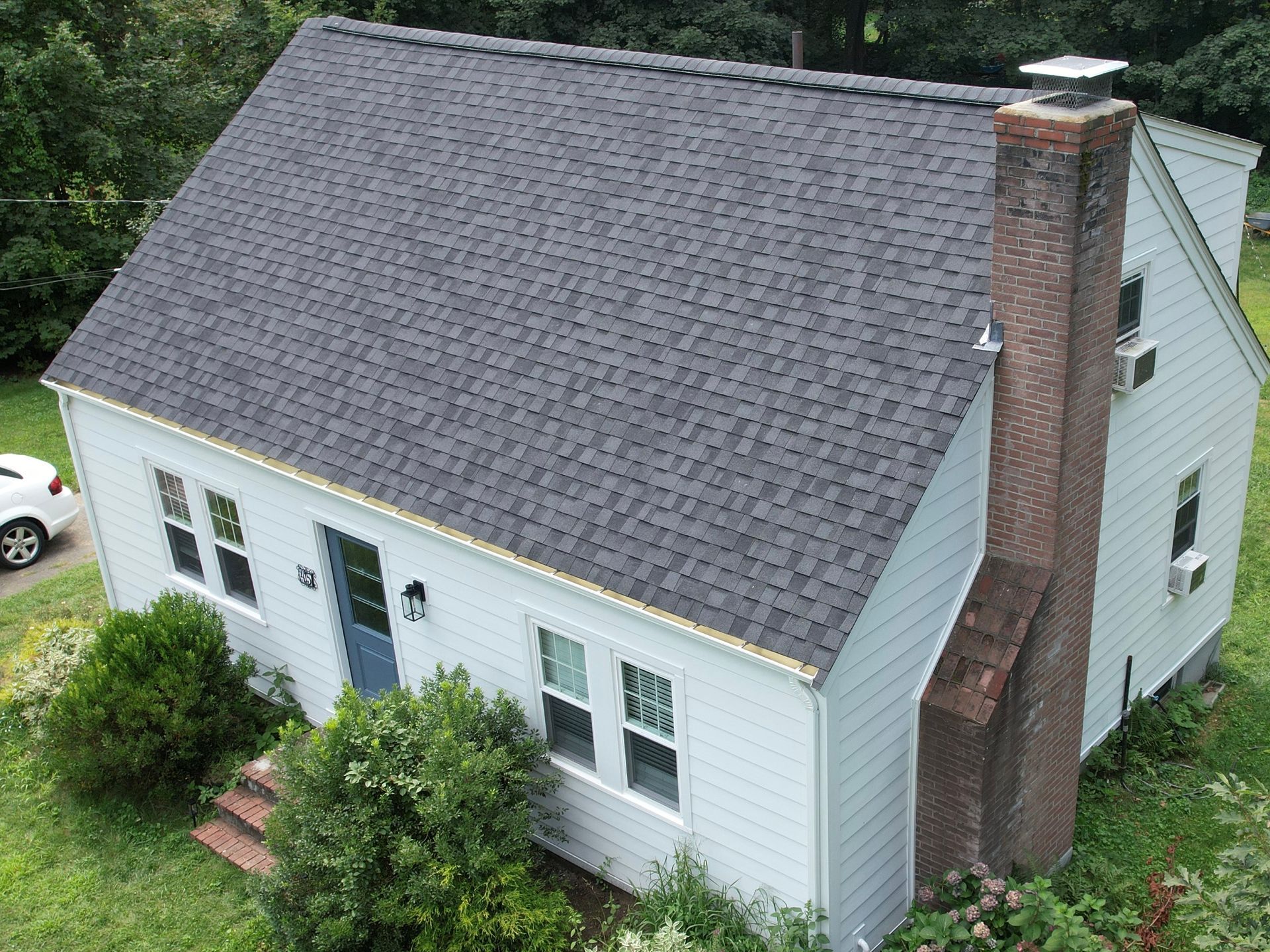 An aerial view of a white house with a black roof.
