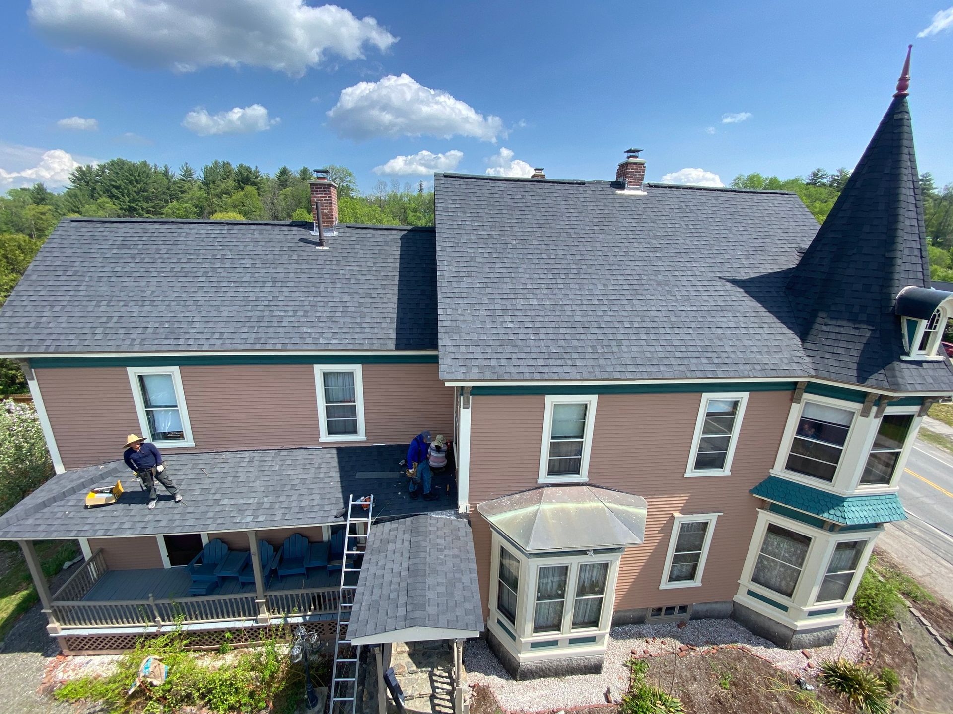 A group of people are working on the roof of a large house.