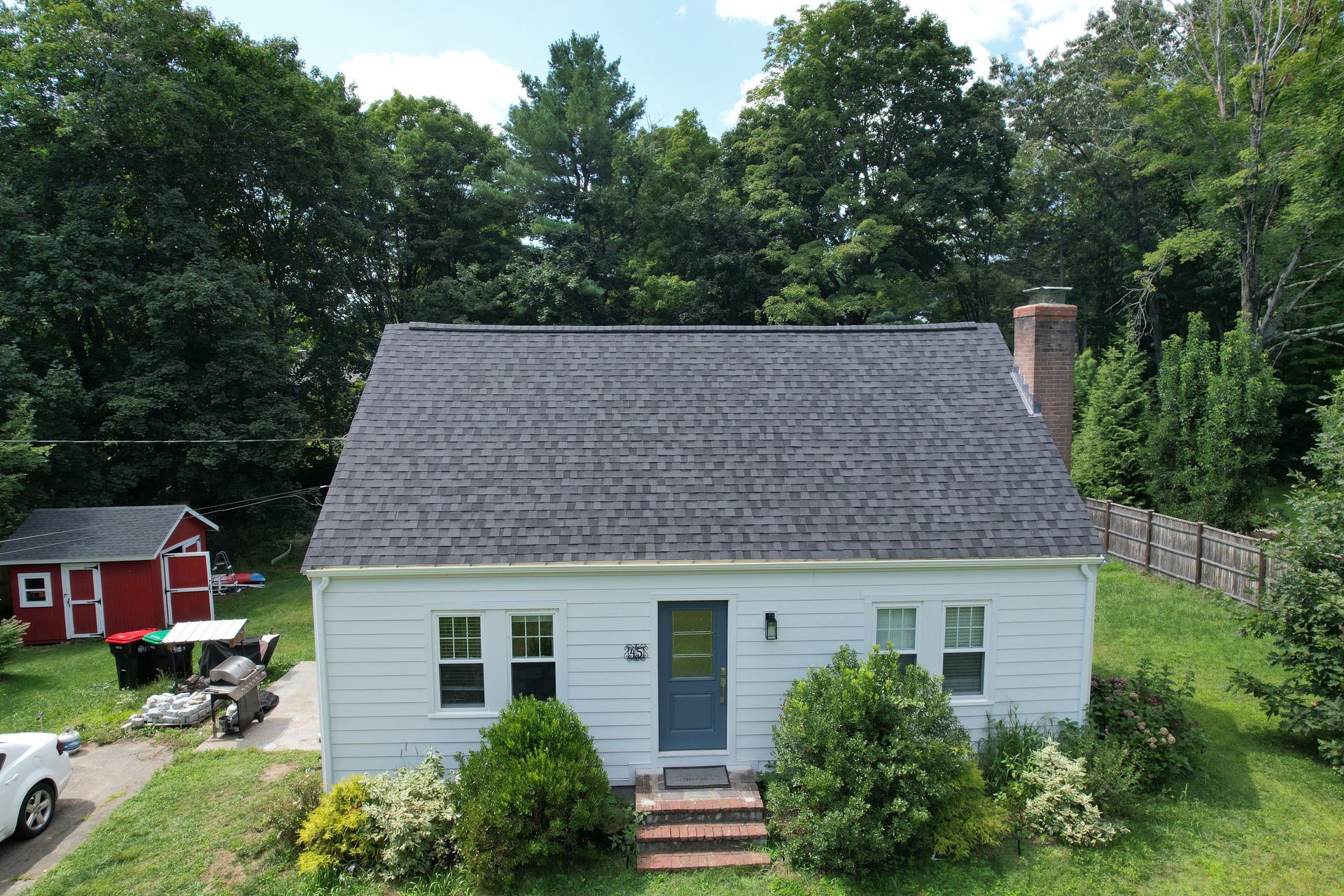 An aerial view of a white house with a black roof