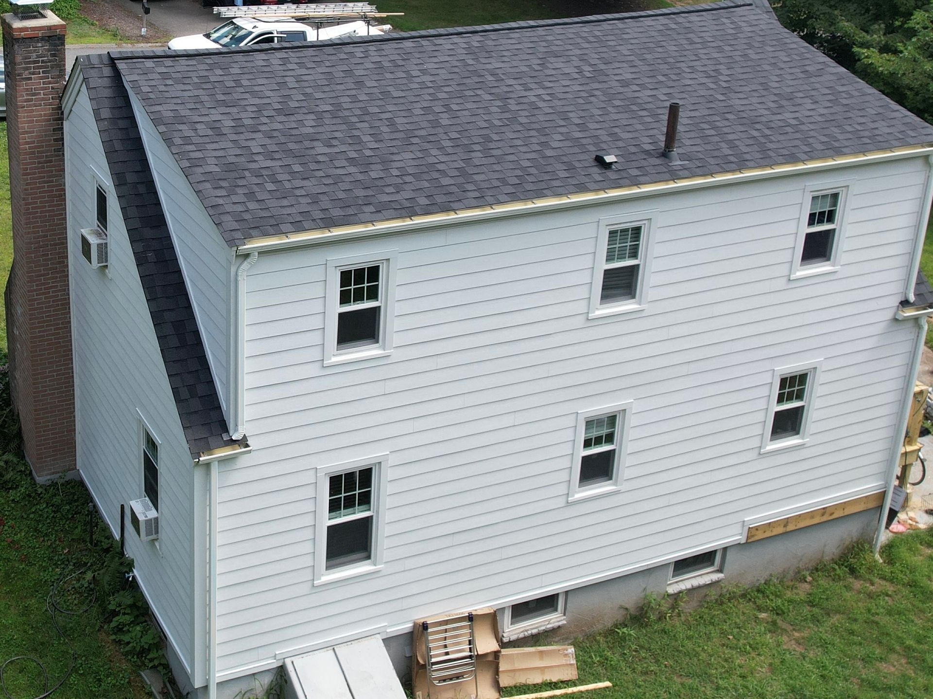 An aerial view of a white house with a black roof.