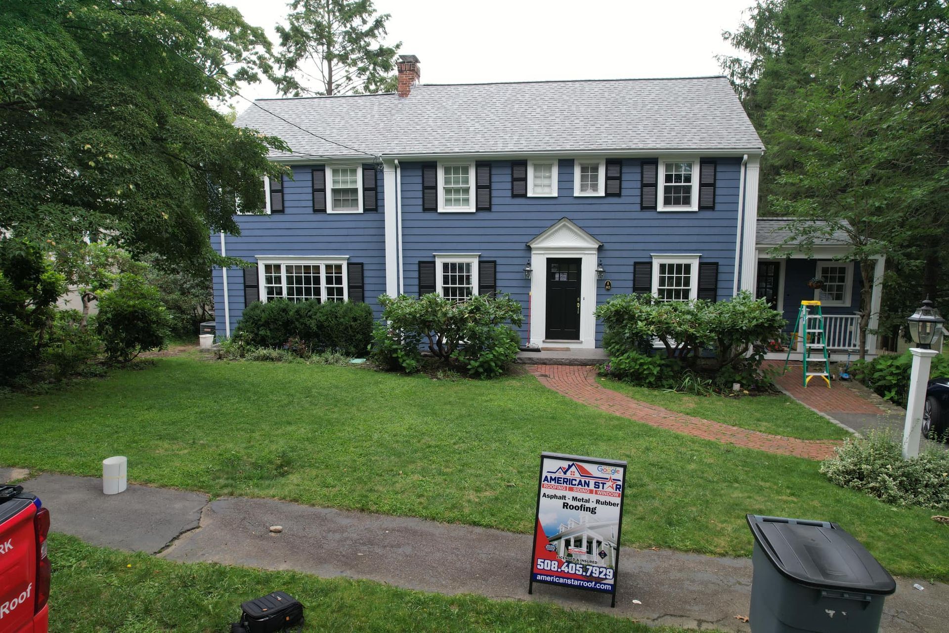 A blue house with white shutters and a sign in front of it