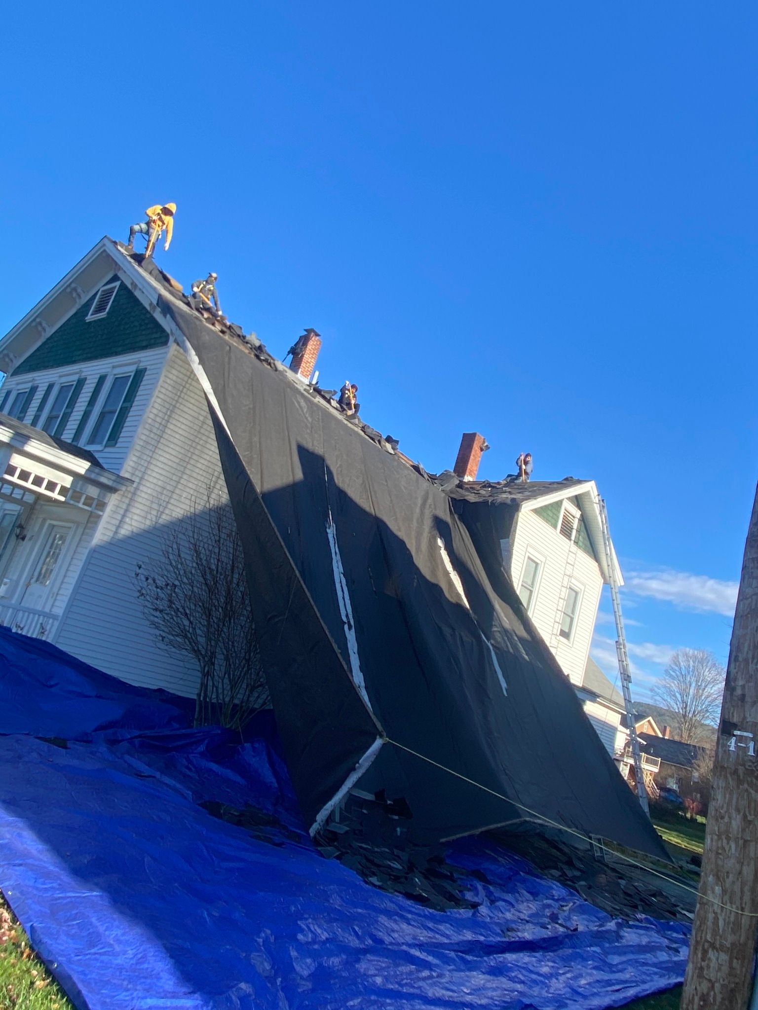 A house is sitting on its side with a blue tarp on the ground.