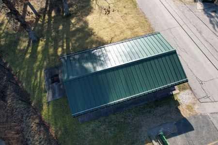 An aerial view of a green metal roof next to a road.