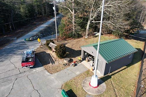 An aerial view of a building with a green roof and a flag pole.