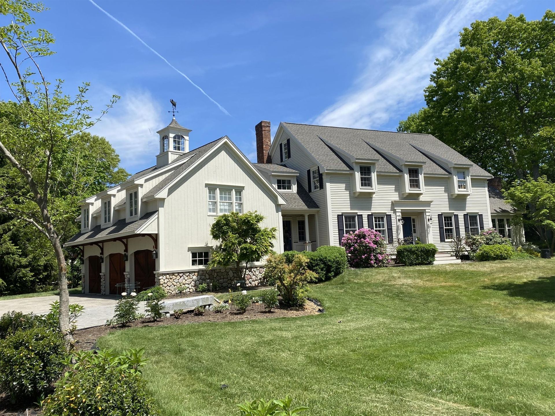 A large white house is sitting on top of a lush green hill.