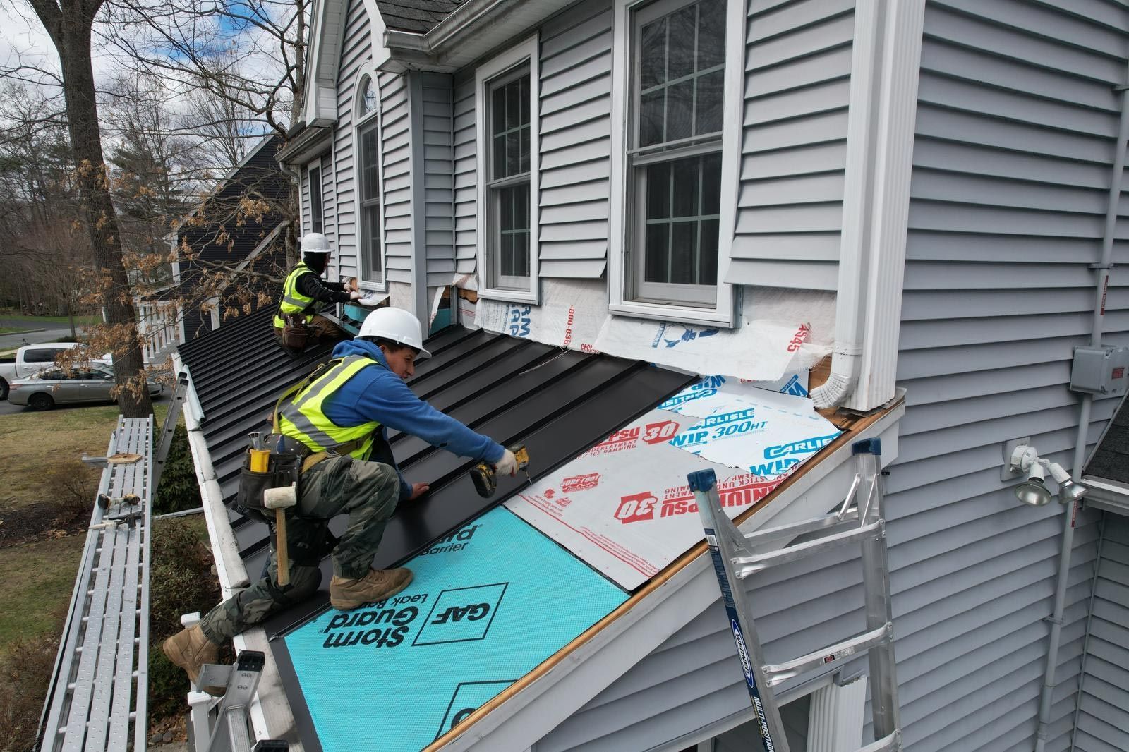 A group of men are working on the roof of a house.
