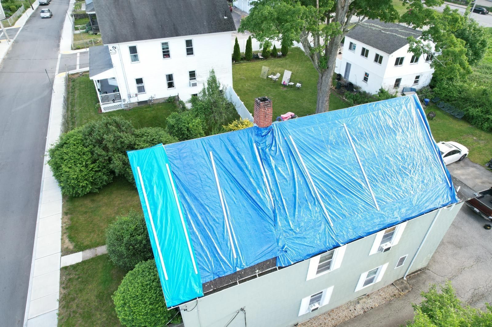 An aerial view of a house with a blue tarp on the roof