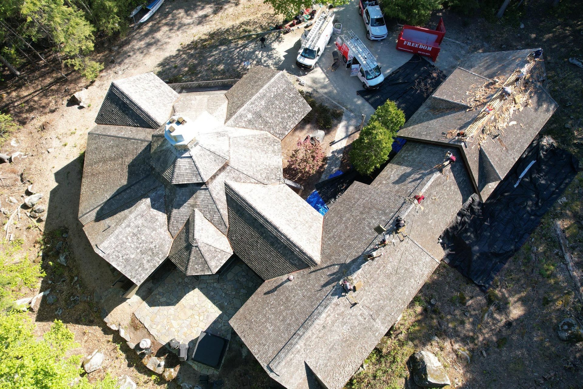 An aerial view of a large house with a lot of roofs surrounded by trees.