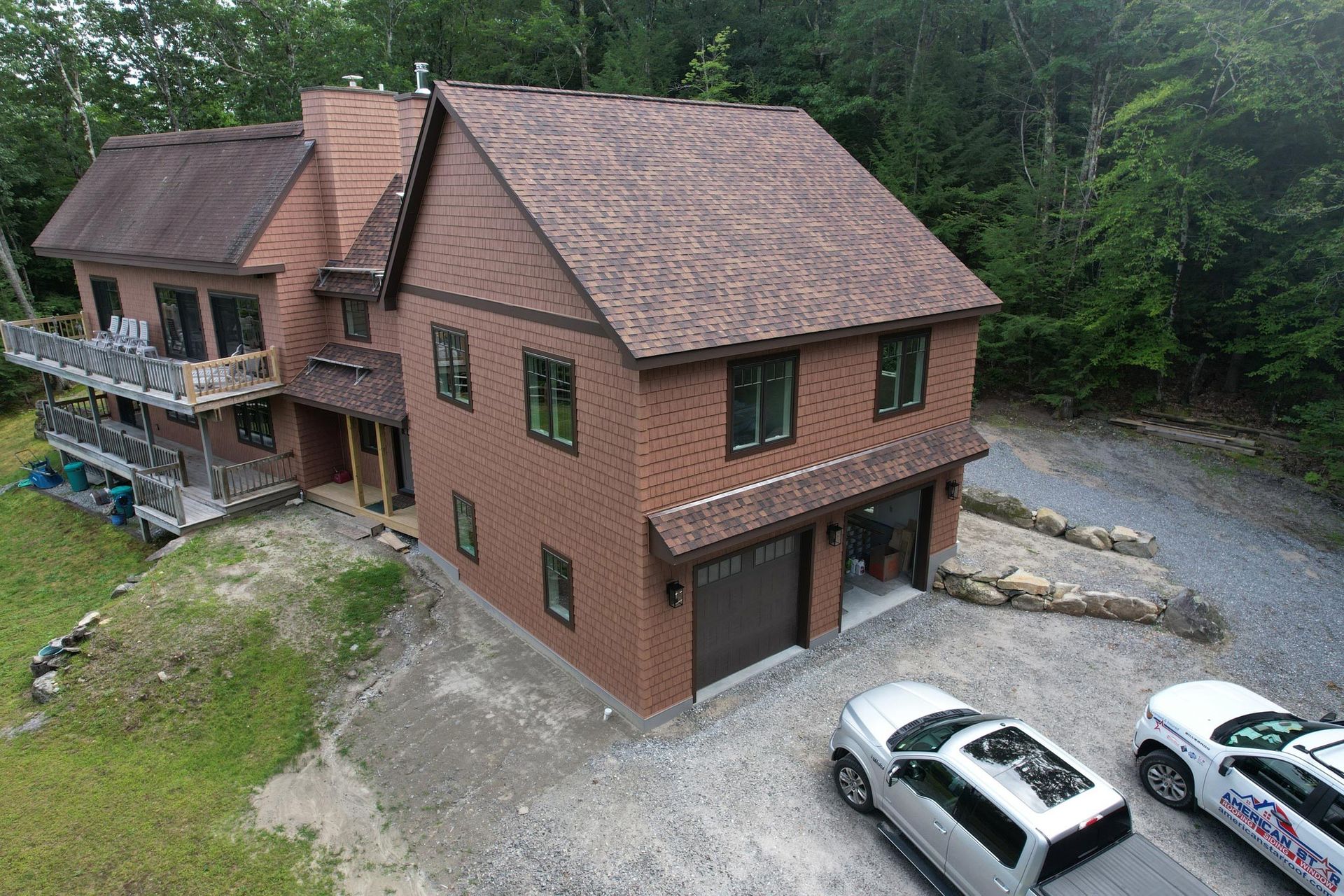 An aerial view of a large brick house with two cars parked in front of it.