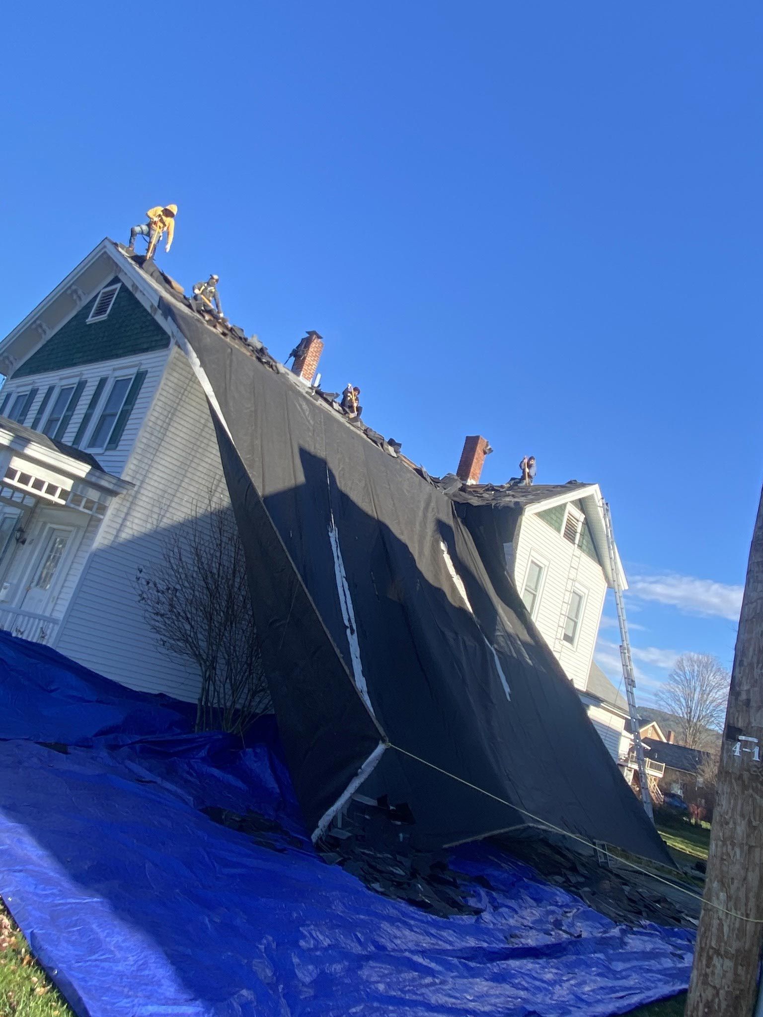 A house is sitting on its side with a blue tarp on the ground.