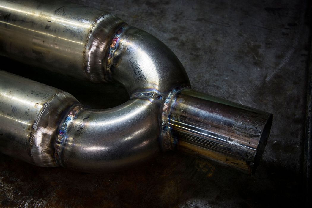 Close-up of shiny welded metal pipes joined in a dark industrial setting