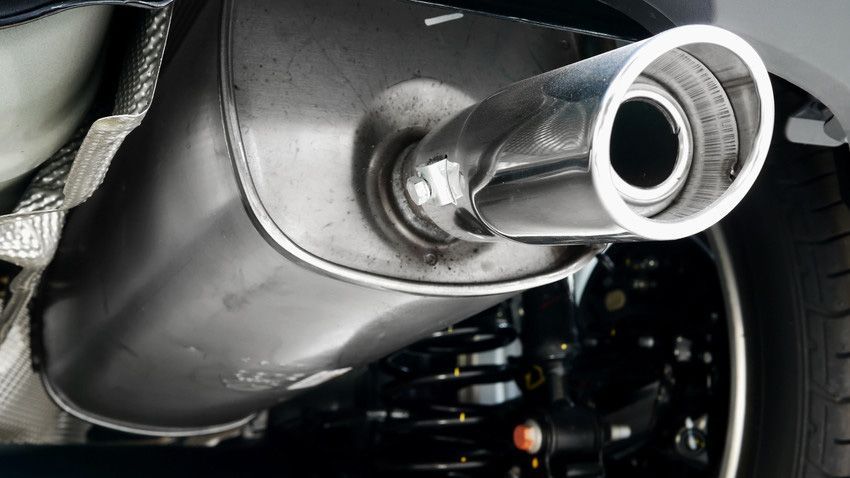 Close-up of a shiny chrome car exhaust pipe beneath the rear bumper