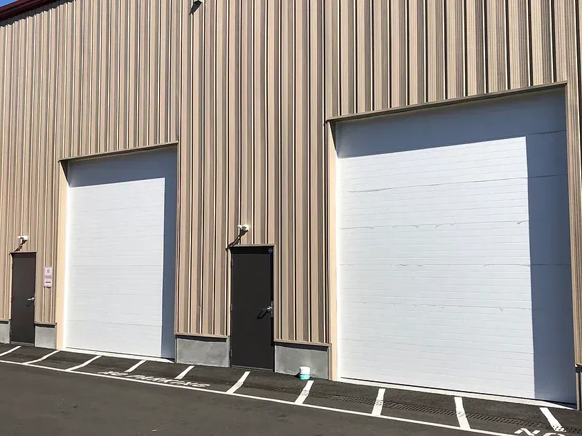 There are two garage doors on the side of a building.