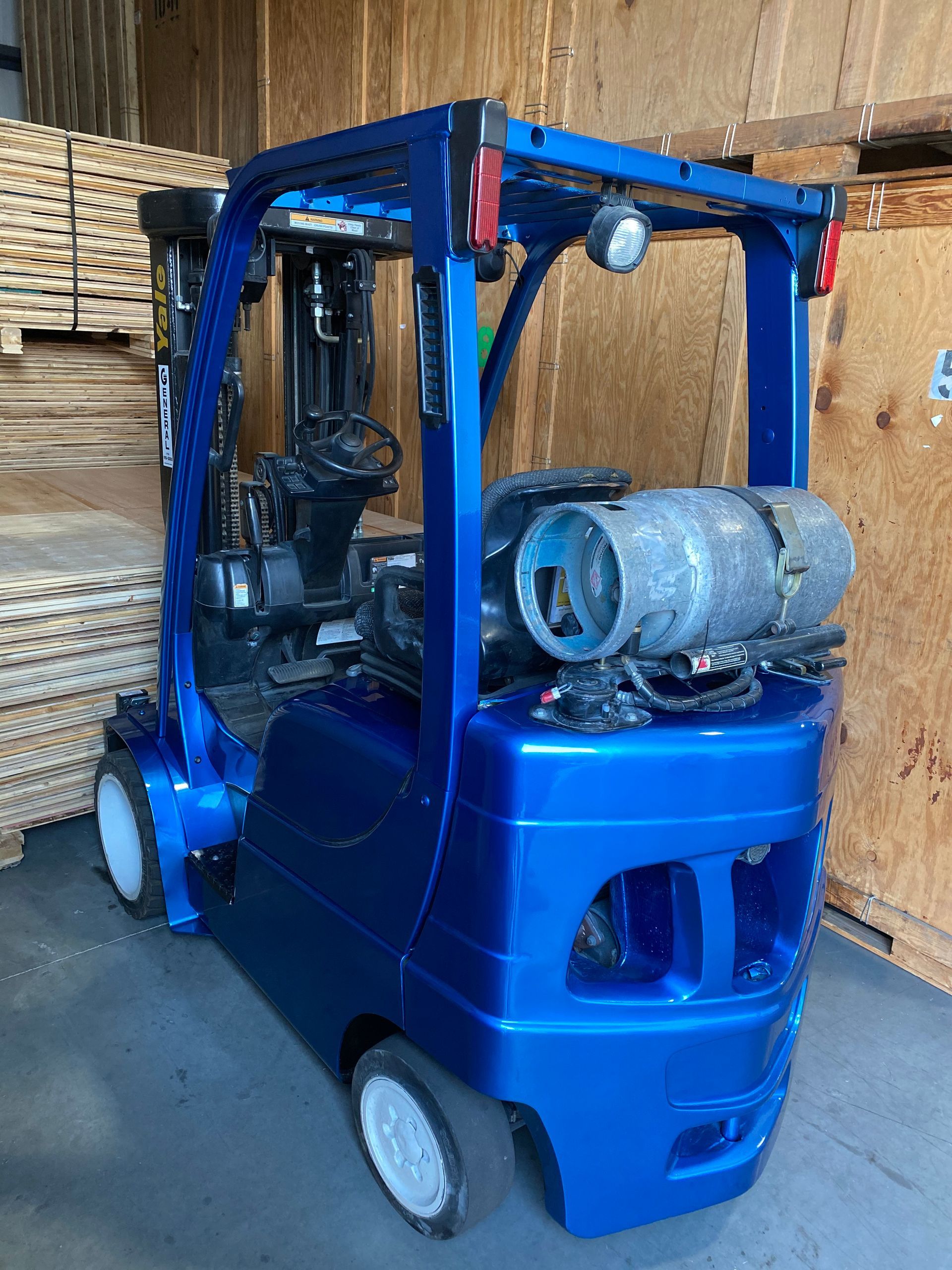 A blue forklift with a propane tank attached to it