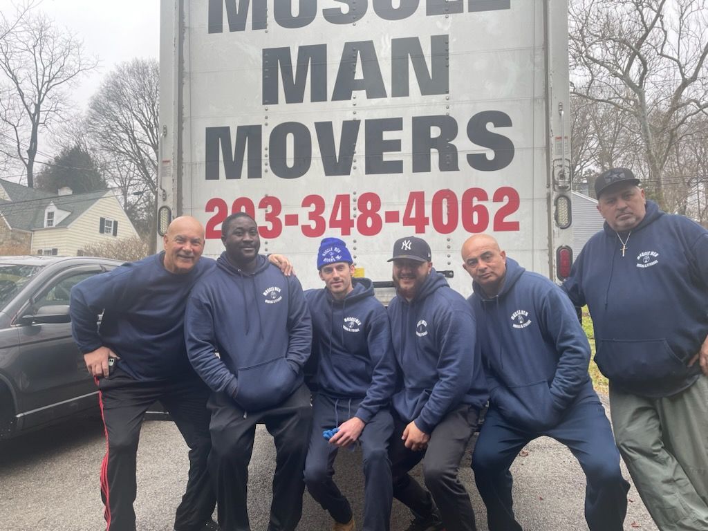 A group of men are posing for a picture in front of a moving truck.