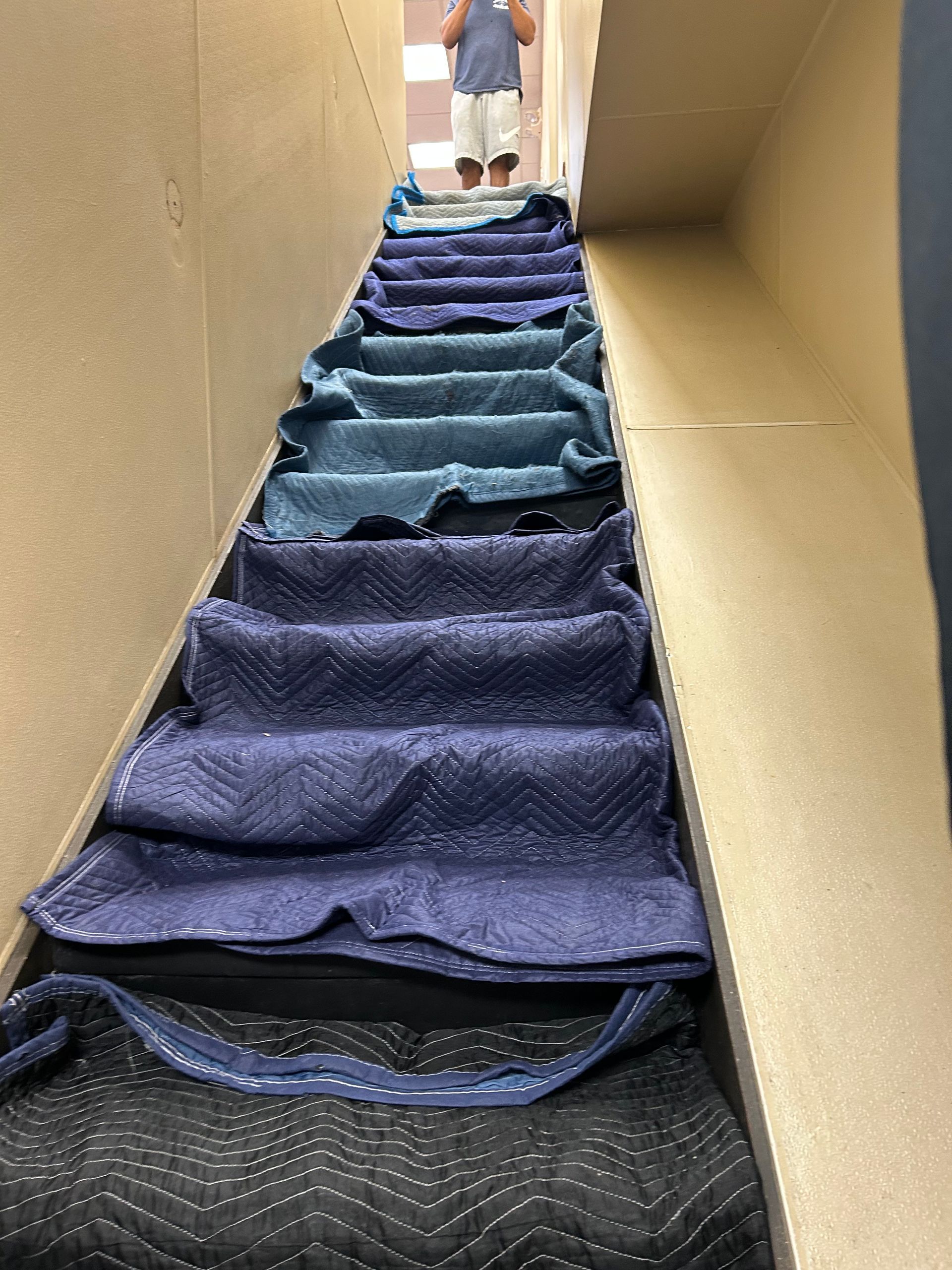 A person is standing on a set of stairs covered in blankets.