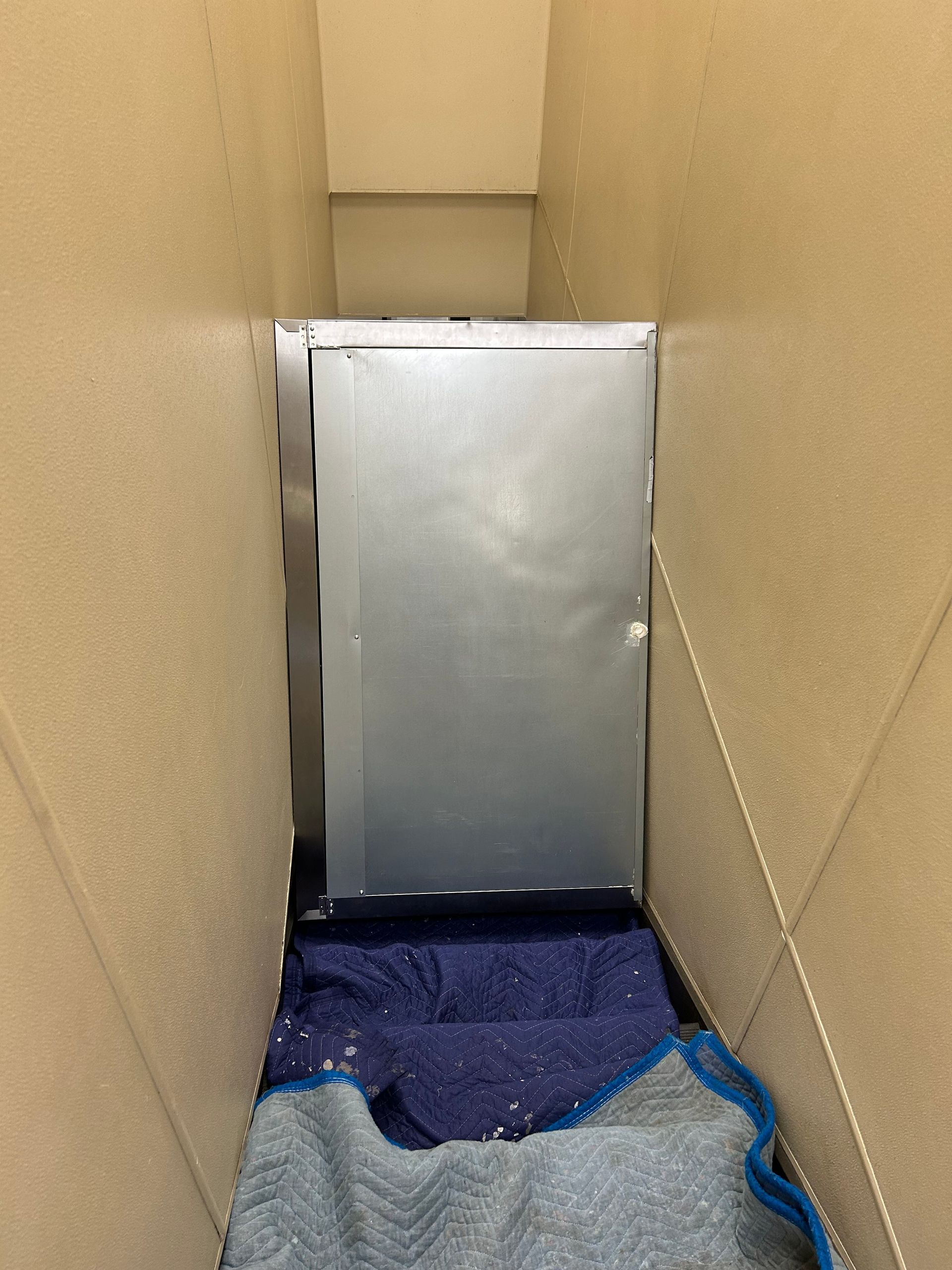 A cardboard box with a blue blanket on the floor