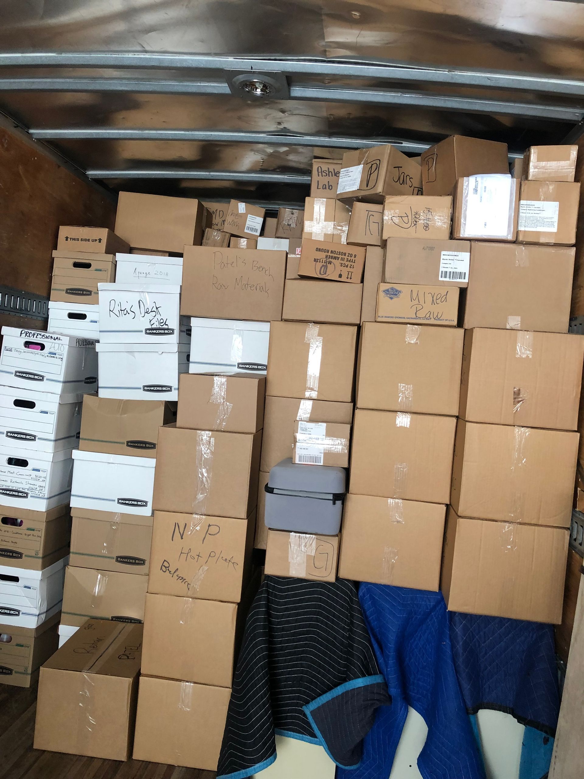 A truck filled with lots of cardboard boxes and a blue blanket