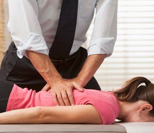 Woman lying on her front side getting adjusted by chiropractor