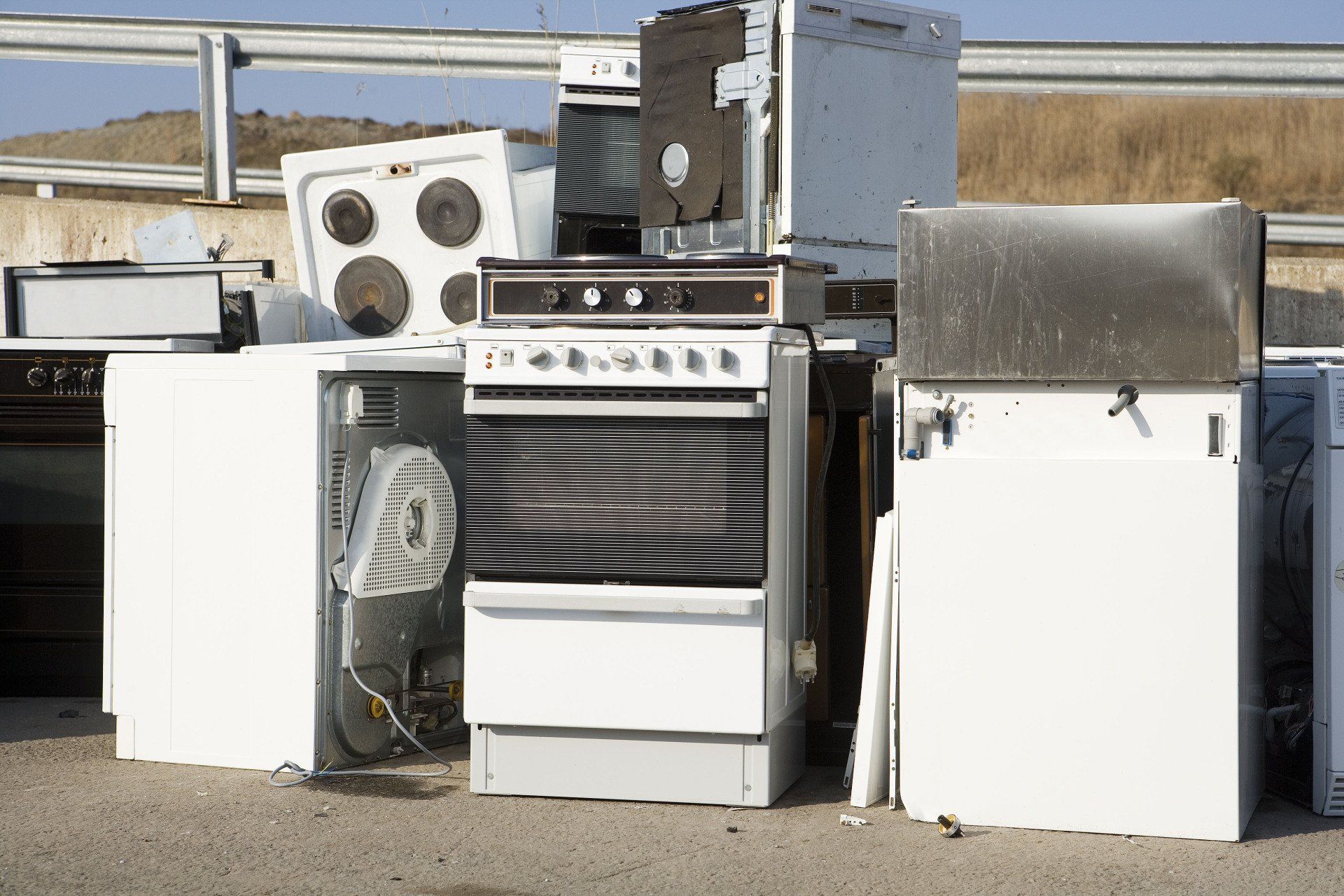 Discarded appliances, including stoves, refrigerators, and washing machines, piled up outdoors.