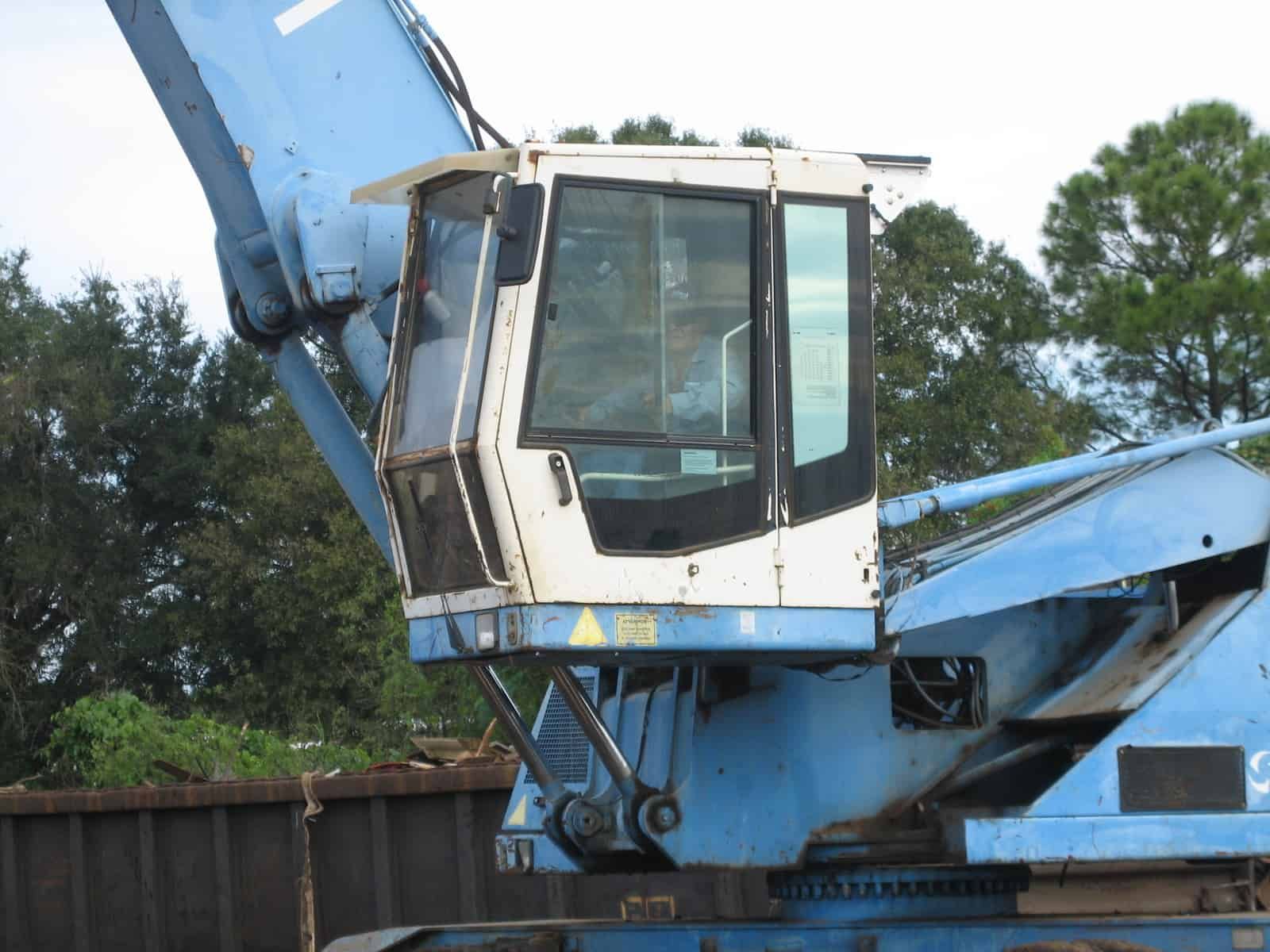 Blue and white excavator cab, with multiple windows, against a green background.
