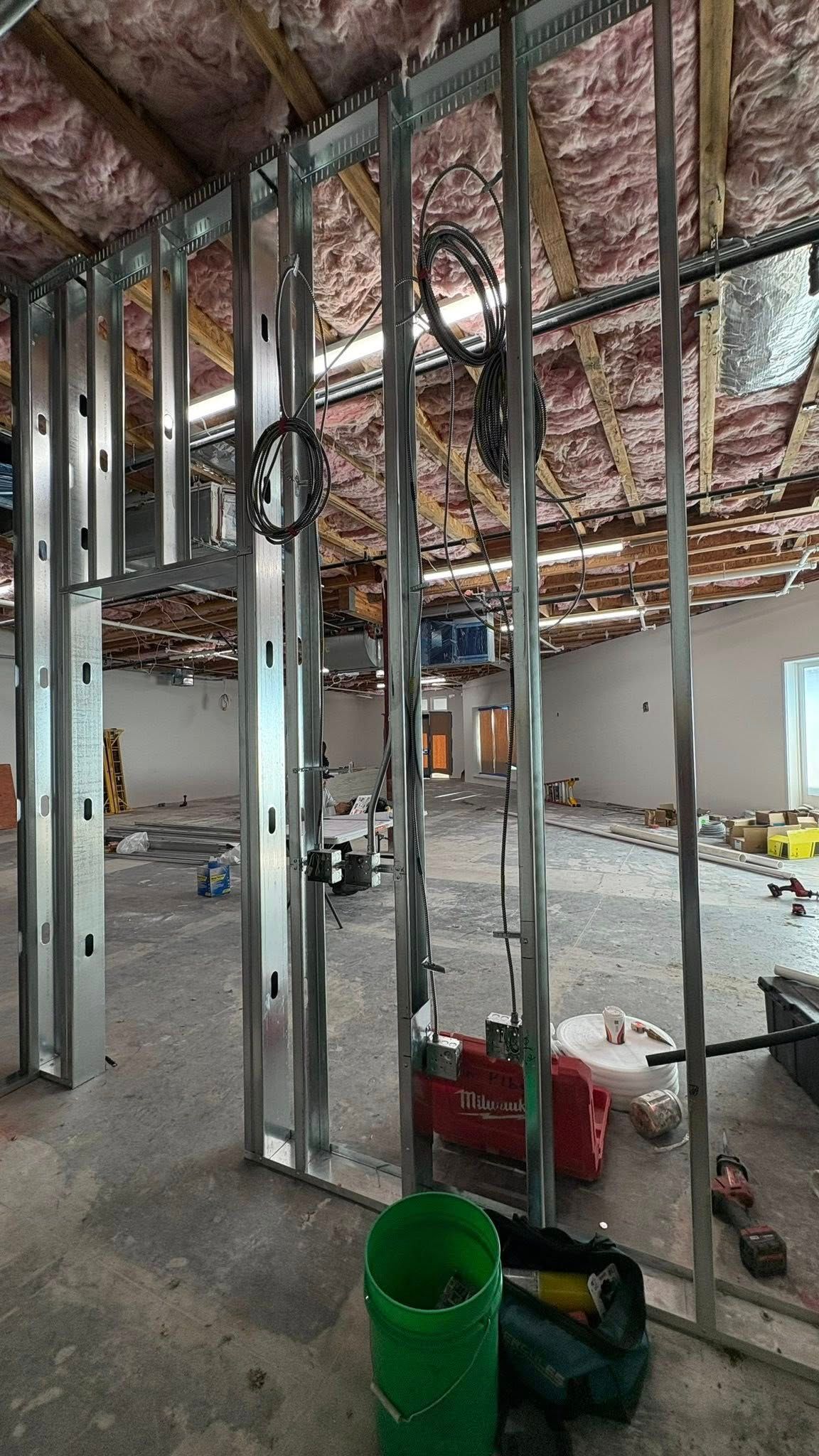 Construction site with metal framing, exposed ceiling insulation, and plumbing.