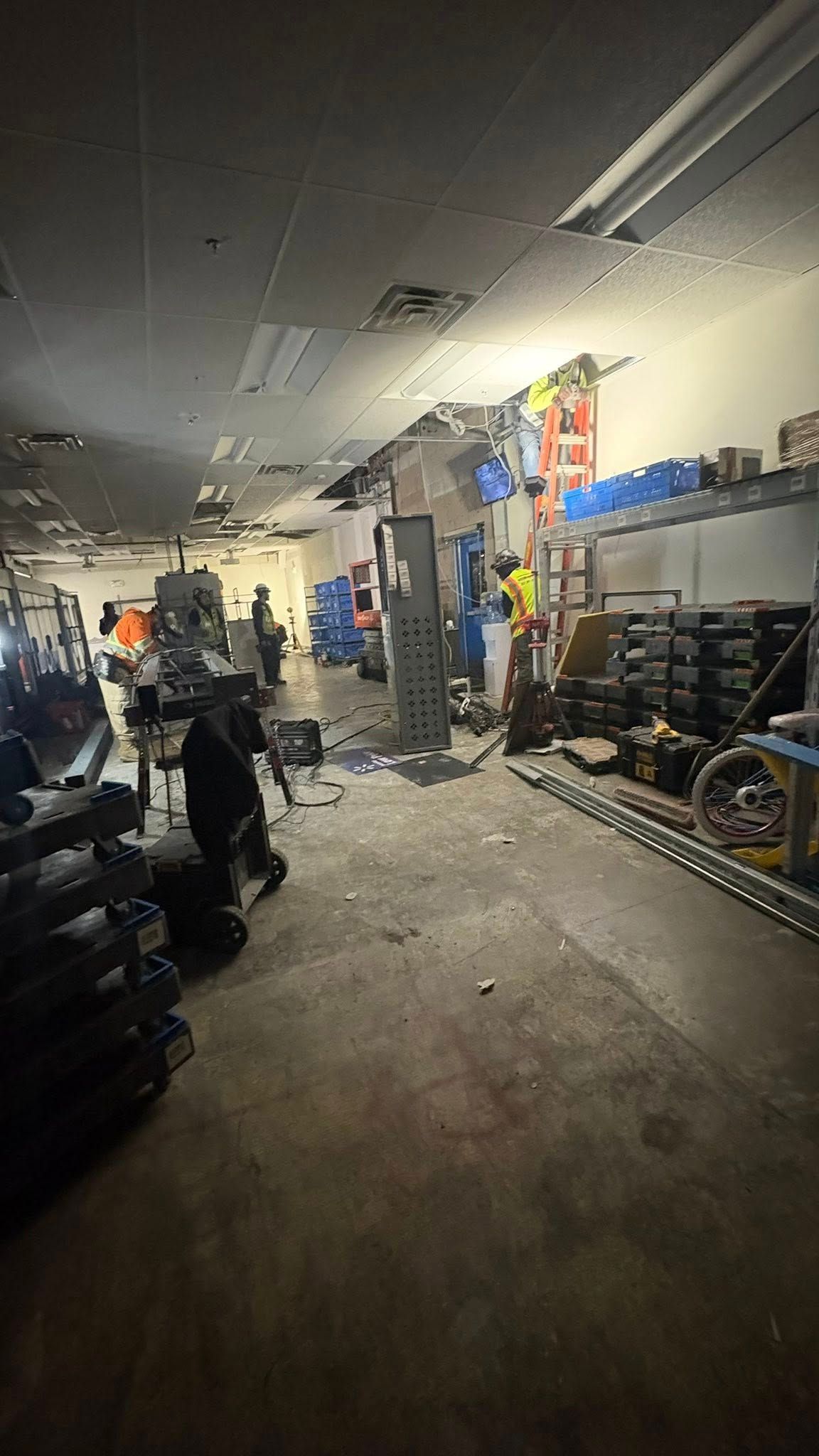 Interior view of a damaged warehouse with debris, tools, and exposed ceiling.