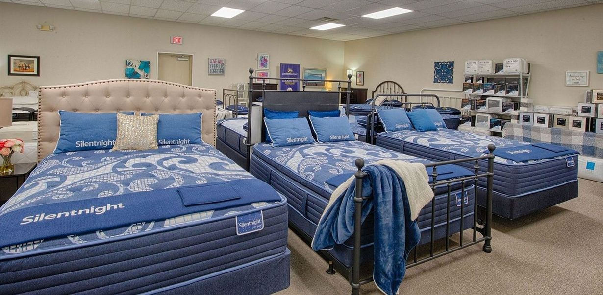 Mattress store interior with several beds on display, blue bedding.