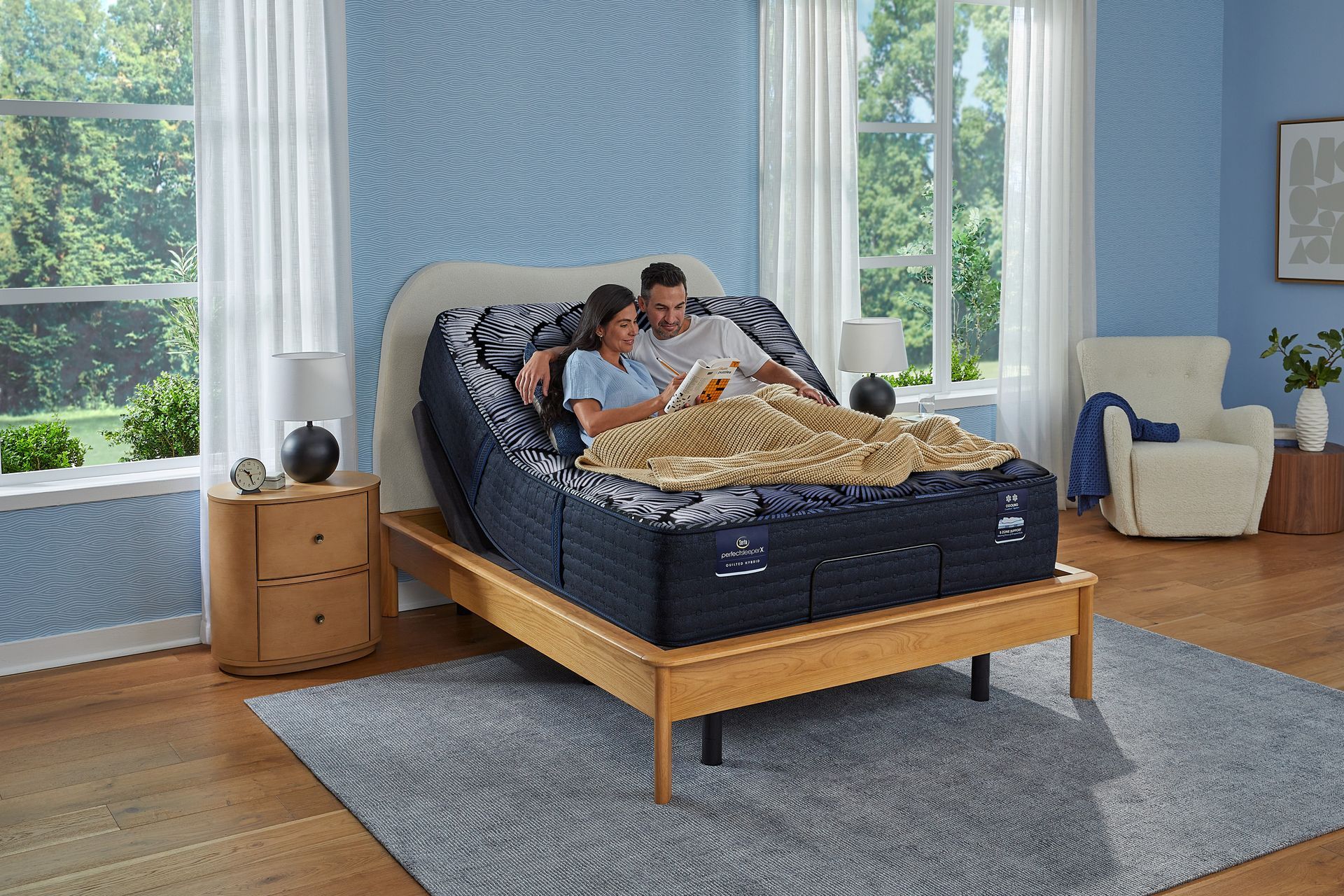 Couple relaxing in bed with adjustable headboard, reading. Blue bedroom, natural light.