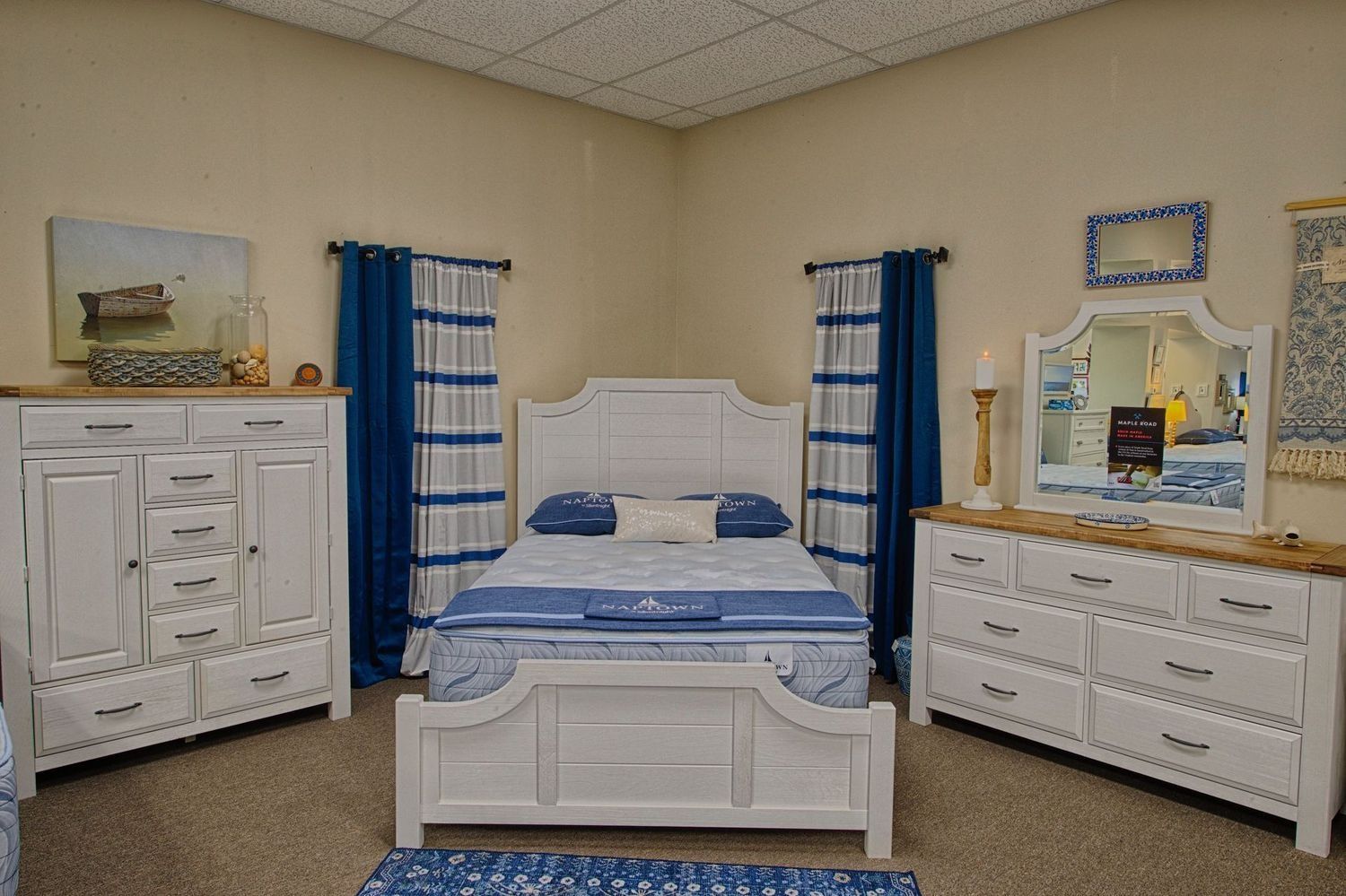 Bedroom set with white furniture, blue curtains, and a blue and white patterned rug.