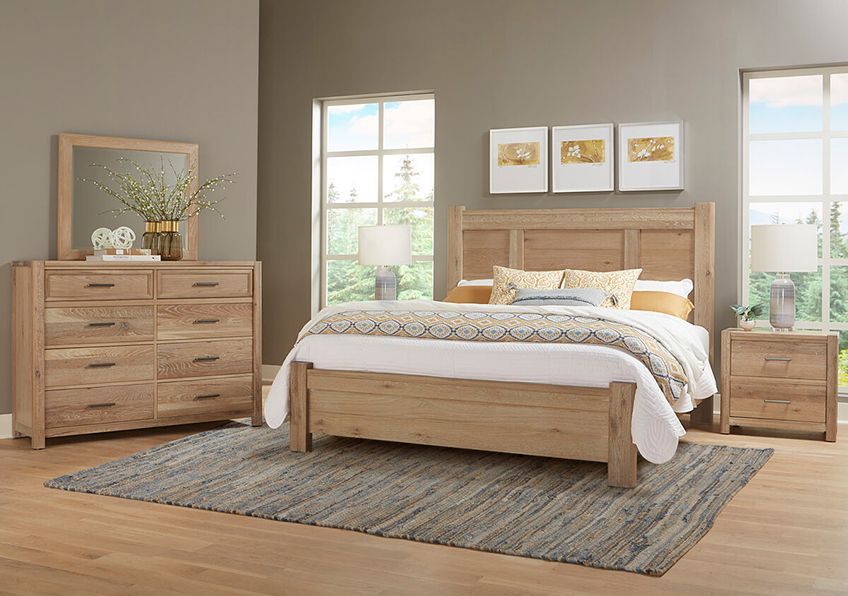 Bedroom set with a bed, dresser, nightstand, and rug. Light wood furniture in a neutral-toned room.