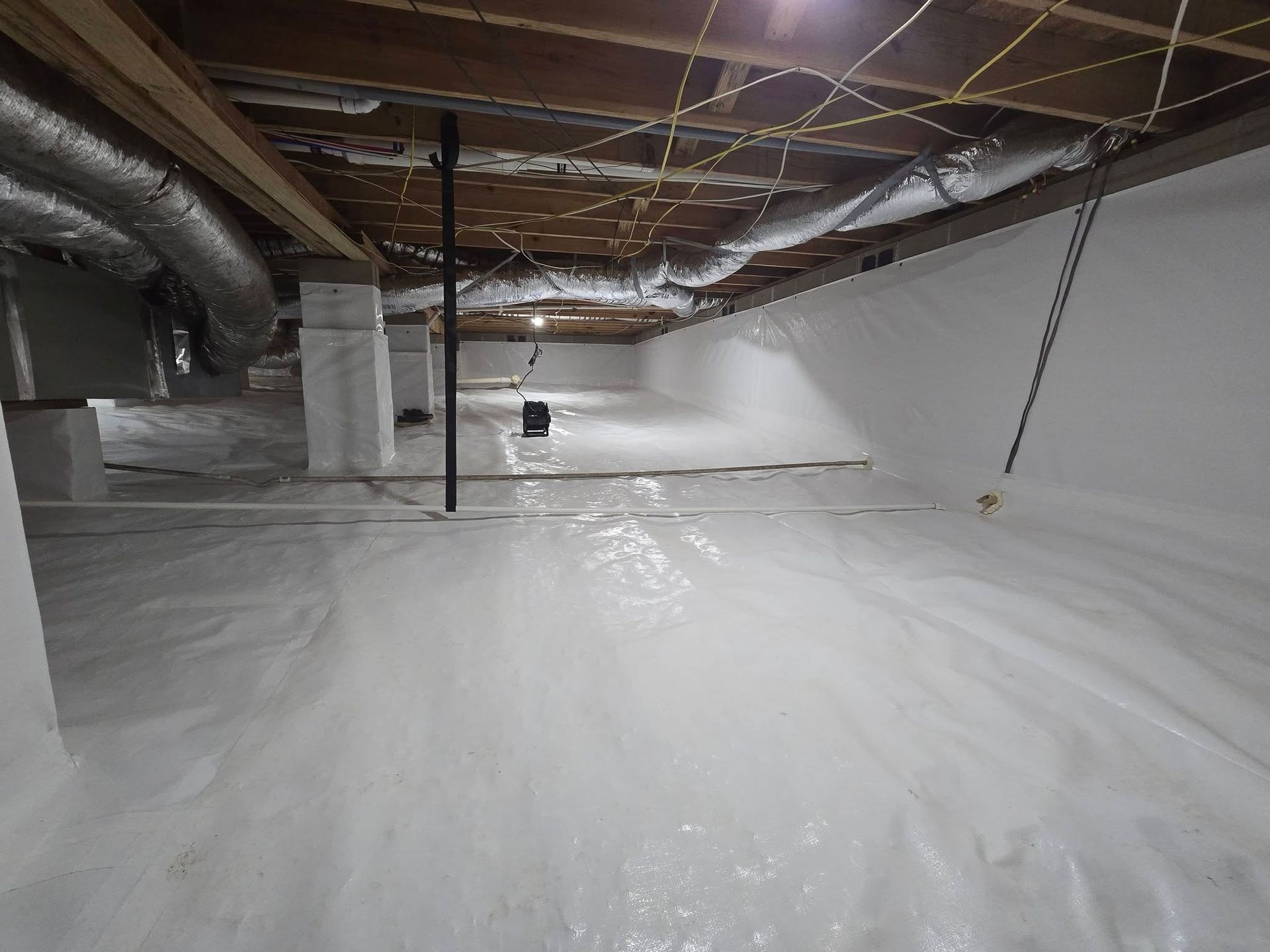 Plastic-covered crawl space with exposed ducts, pipes, and joists under a low ceiling