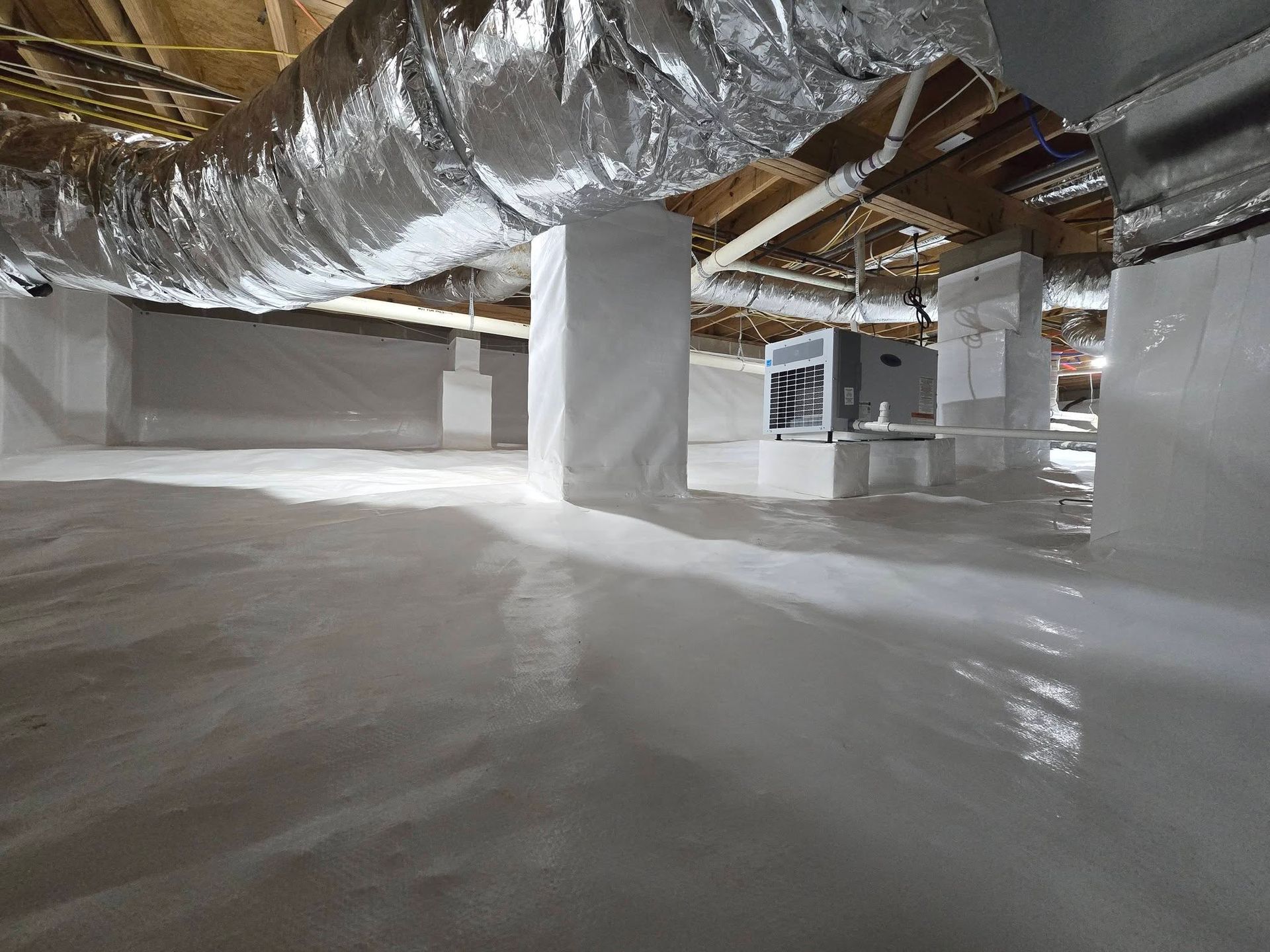 Unfinished basement with exposed ductwork, white columns, and concrete floor under construction.