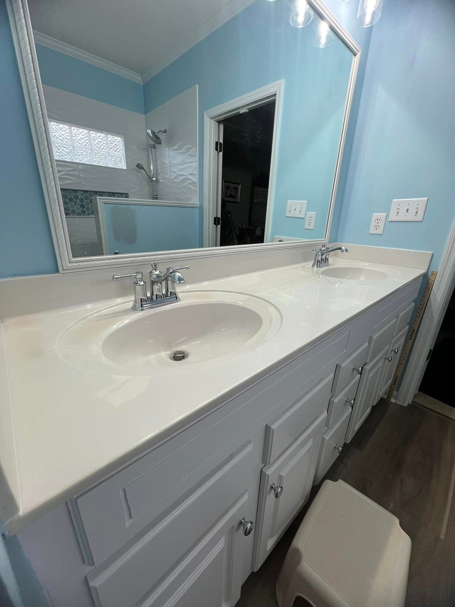 A bathroom with two sinks, a mirror and a stool.