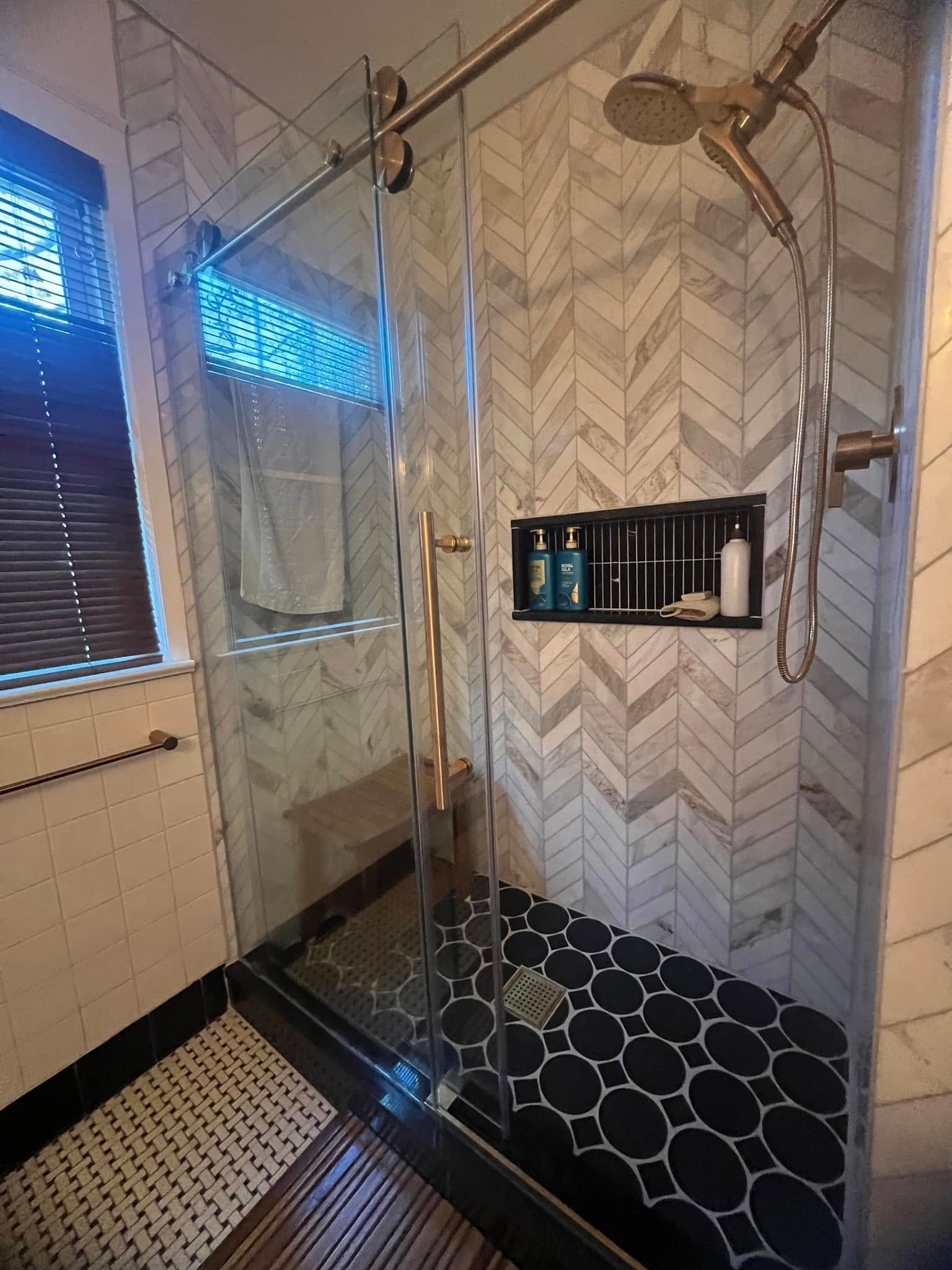 A bathroom with a sliding glass shower door and a window.