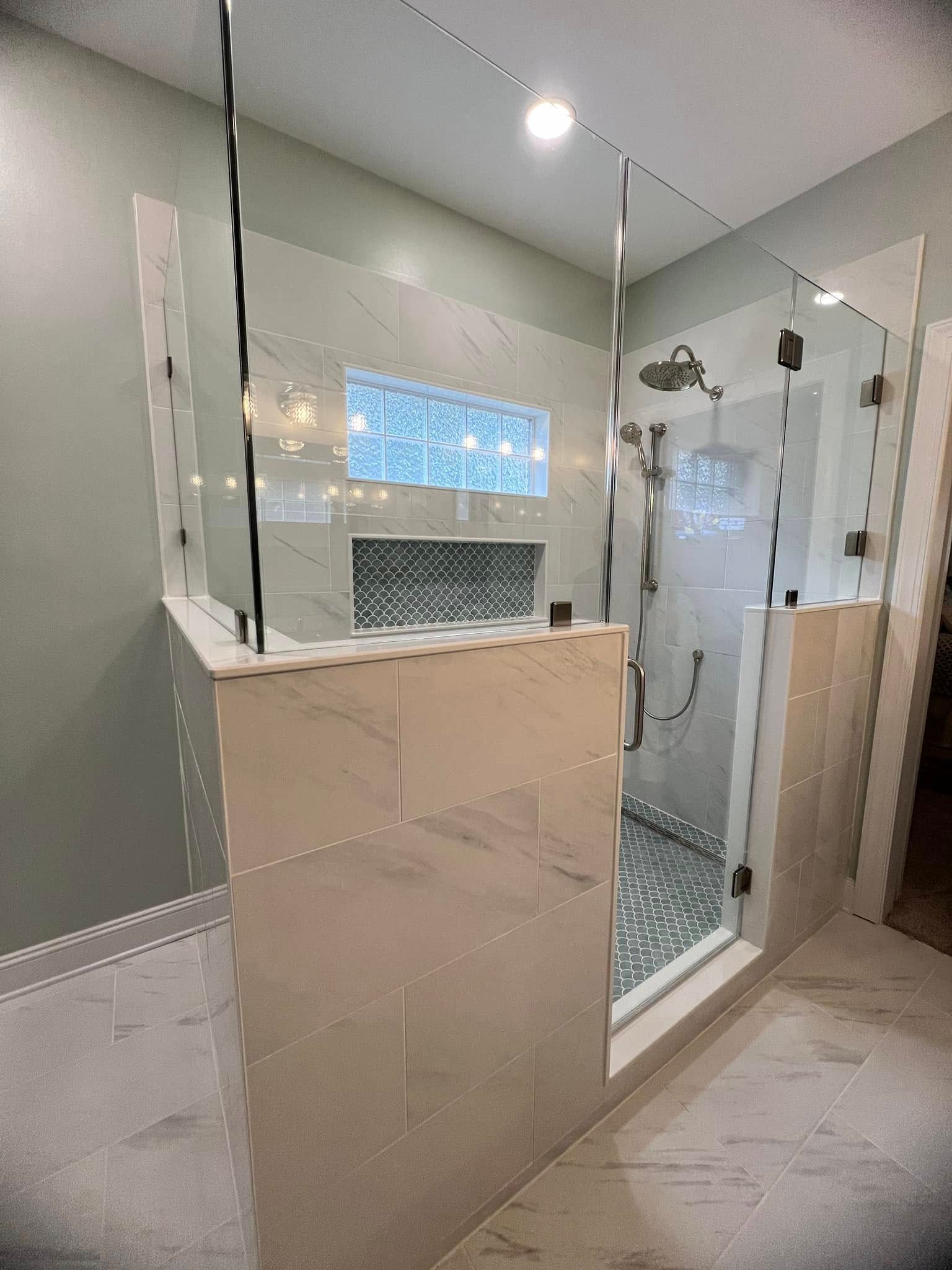 A bathroom with a walk in shower with a glass door.