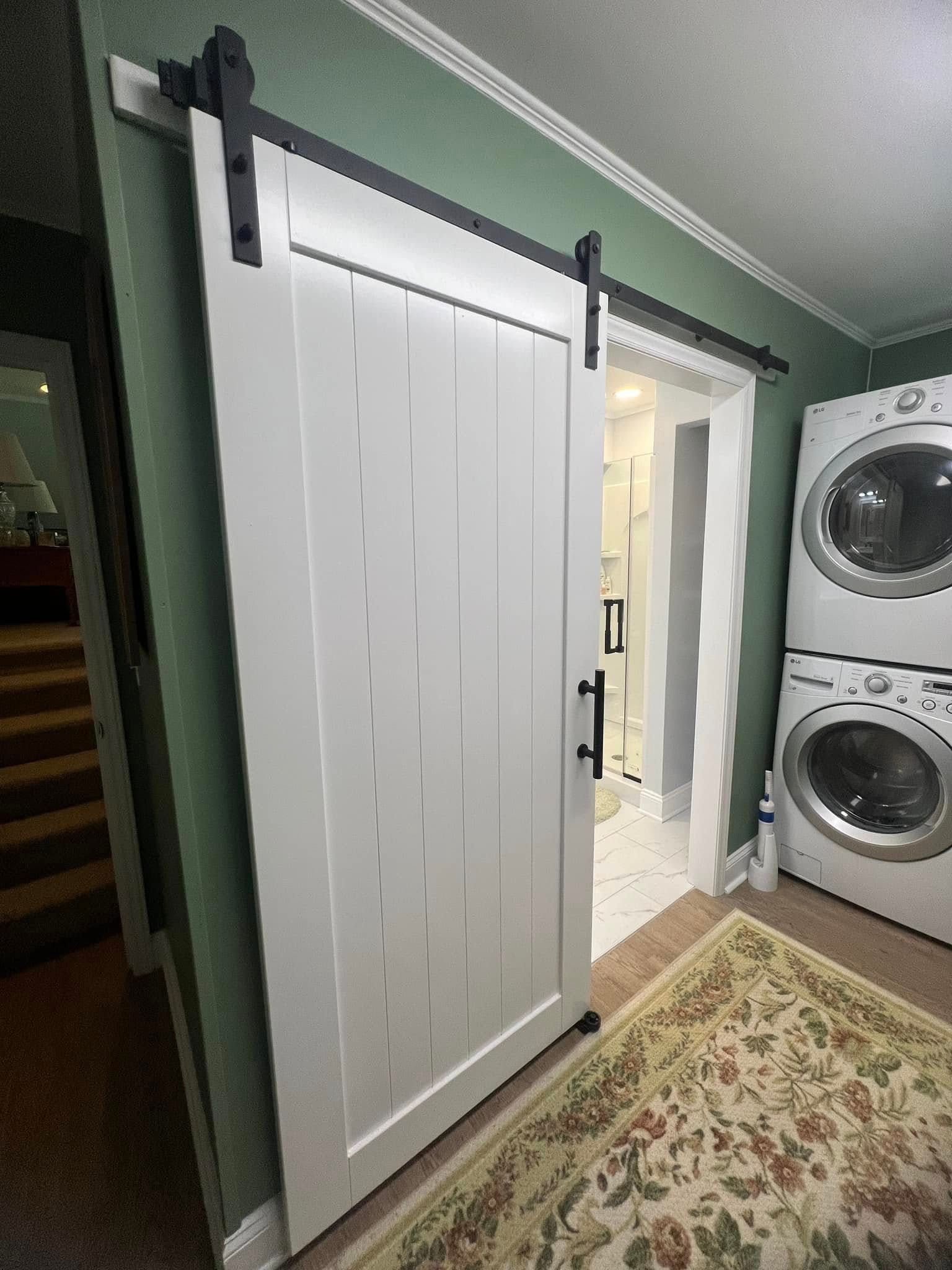 A laundry room with a sliding barn door and a washer and dryer.