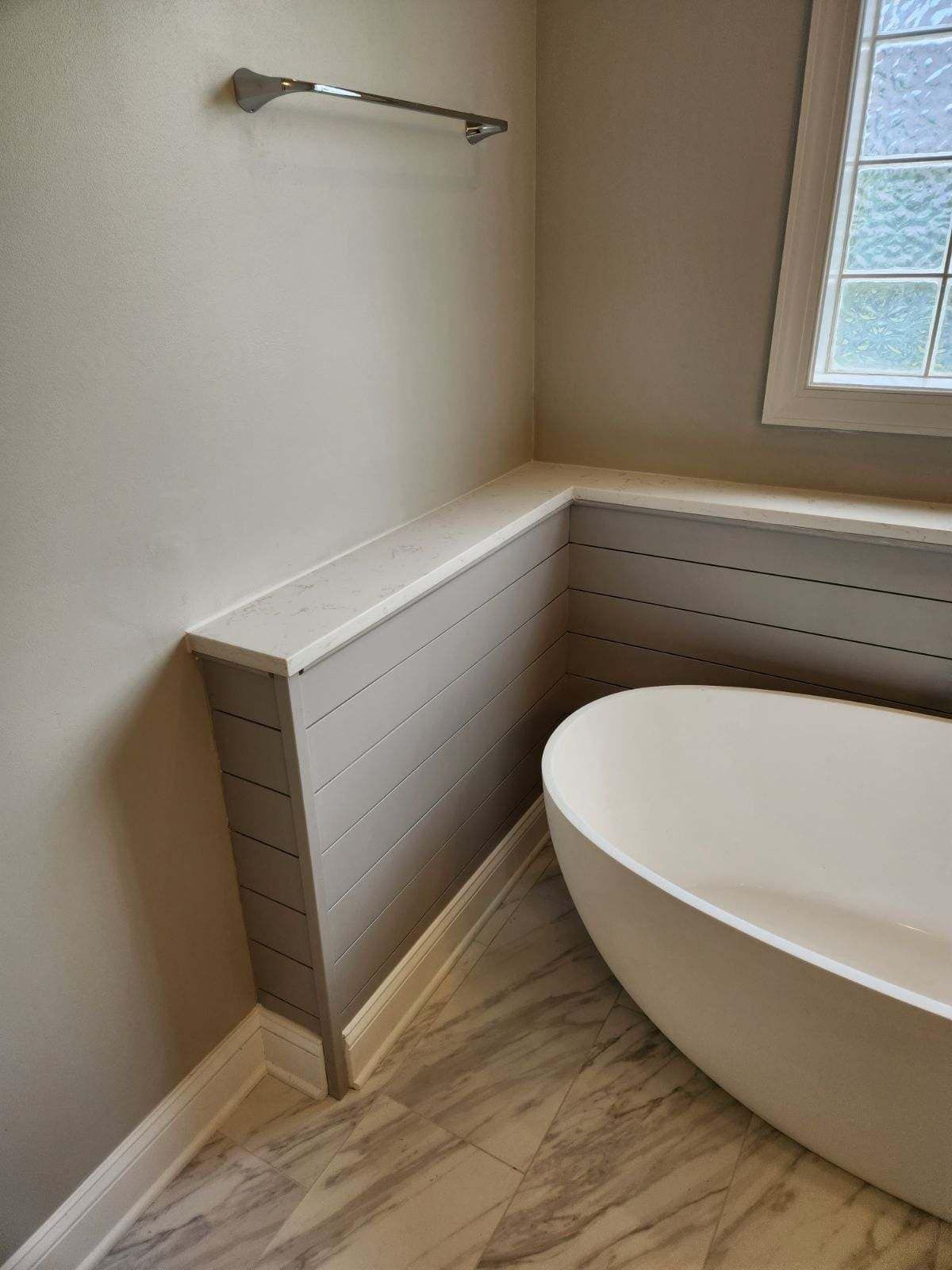 There is a bathtub in the bathroom next to a window.