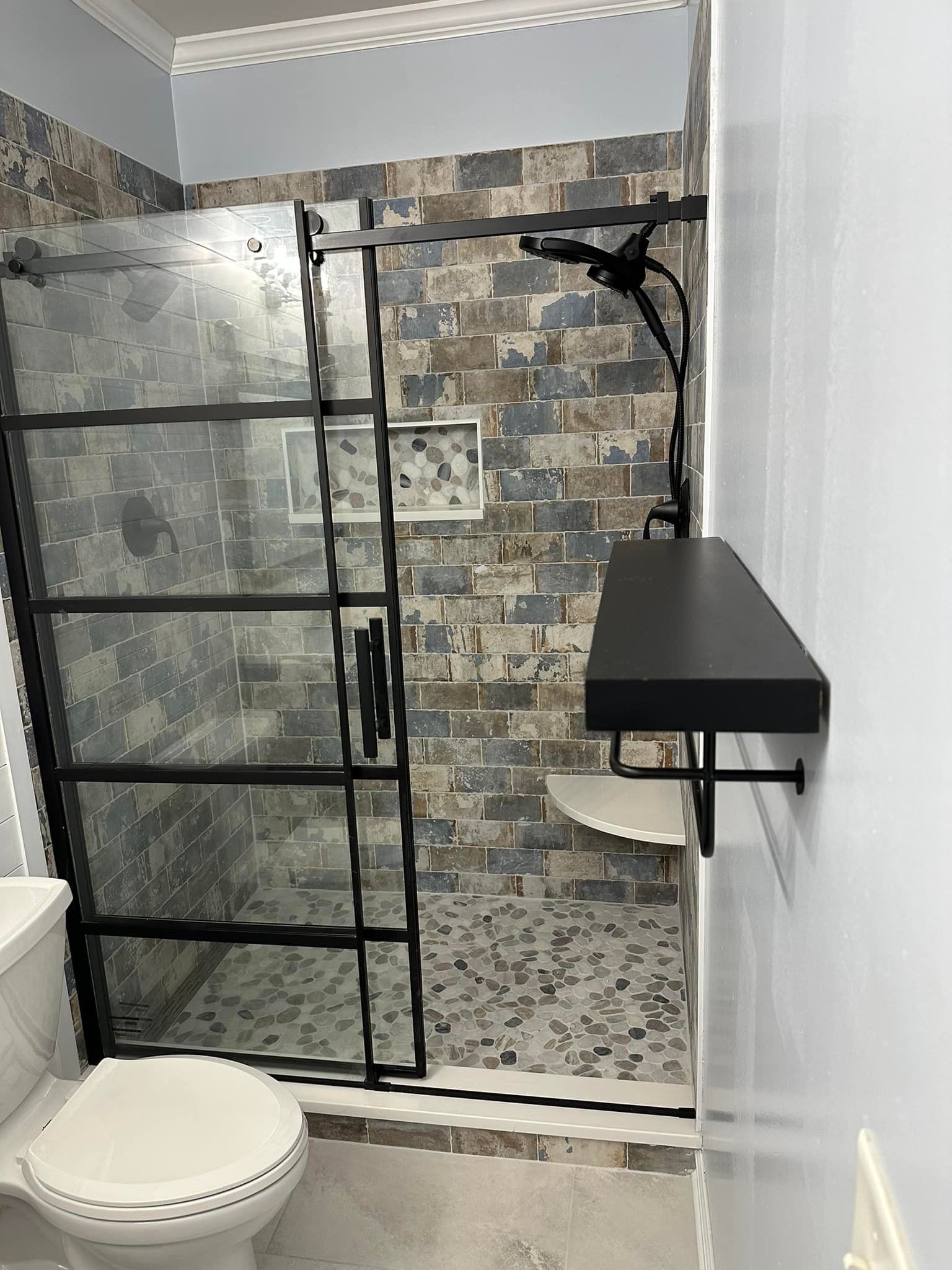 A bathroom with a toilet, shower, and shelf.