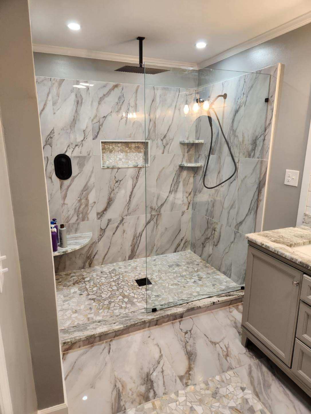 A bathroom with a walk in shower and a sink.