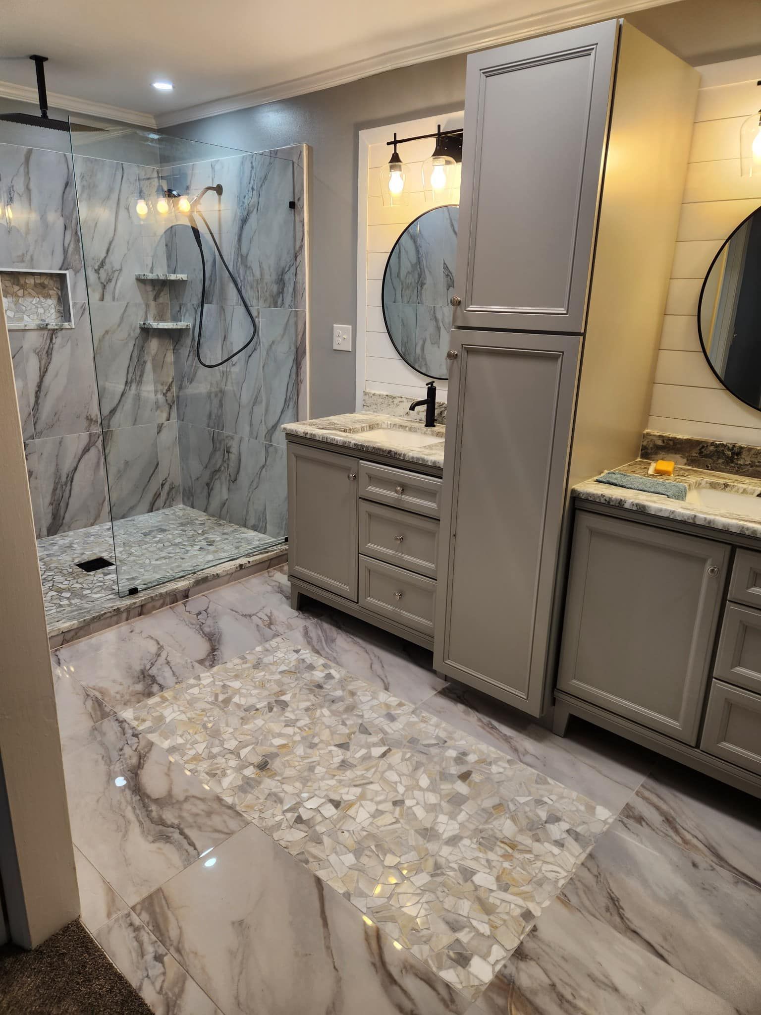 A bathroom with a walk in shower, sink, and cabinets.