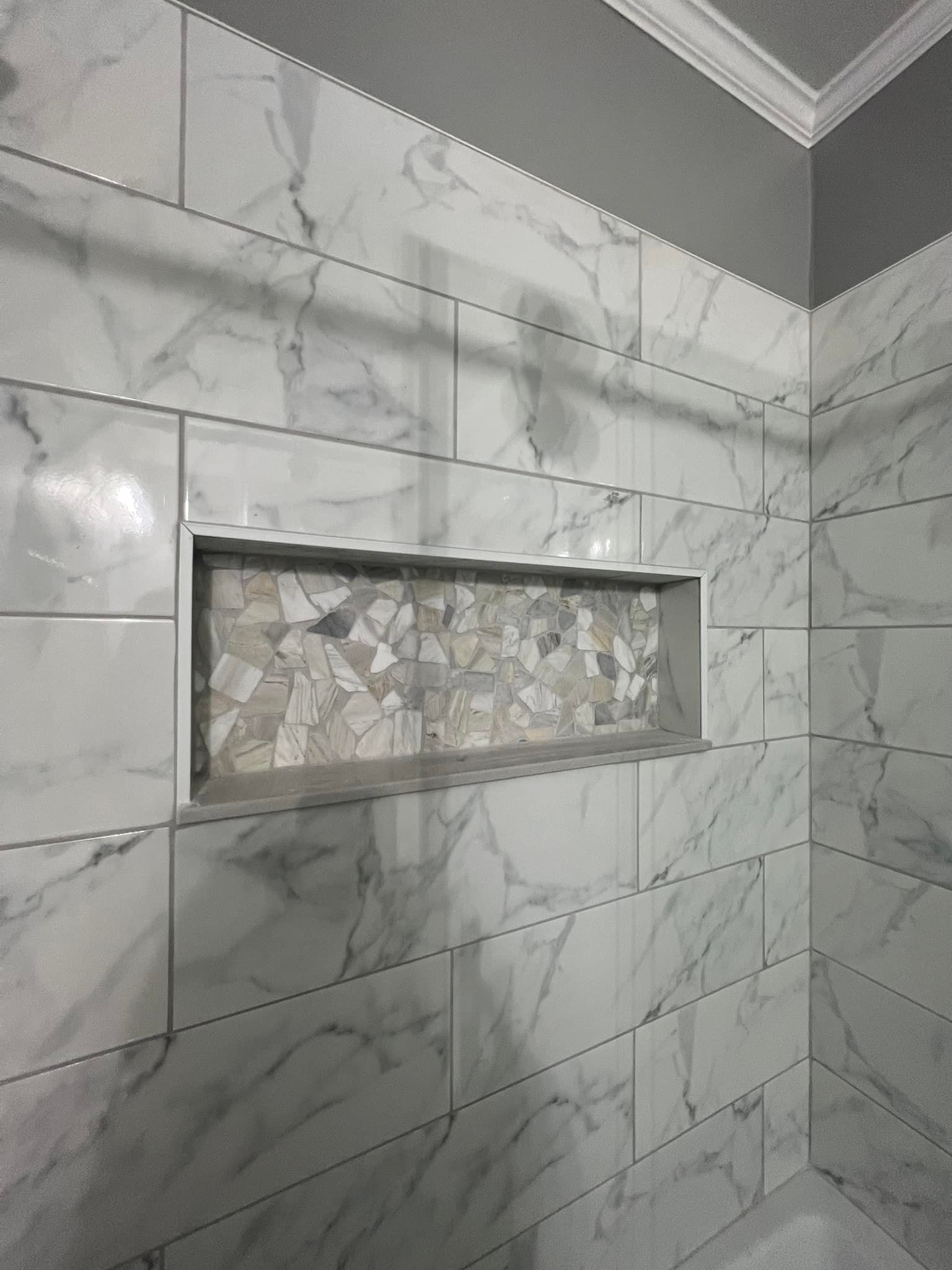 A bathroom with marble tiles and a shower niche.