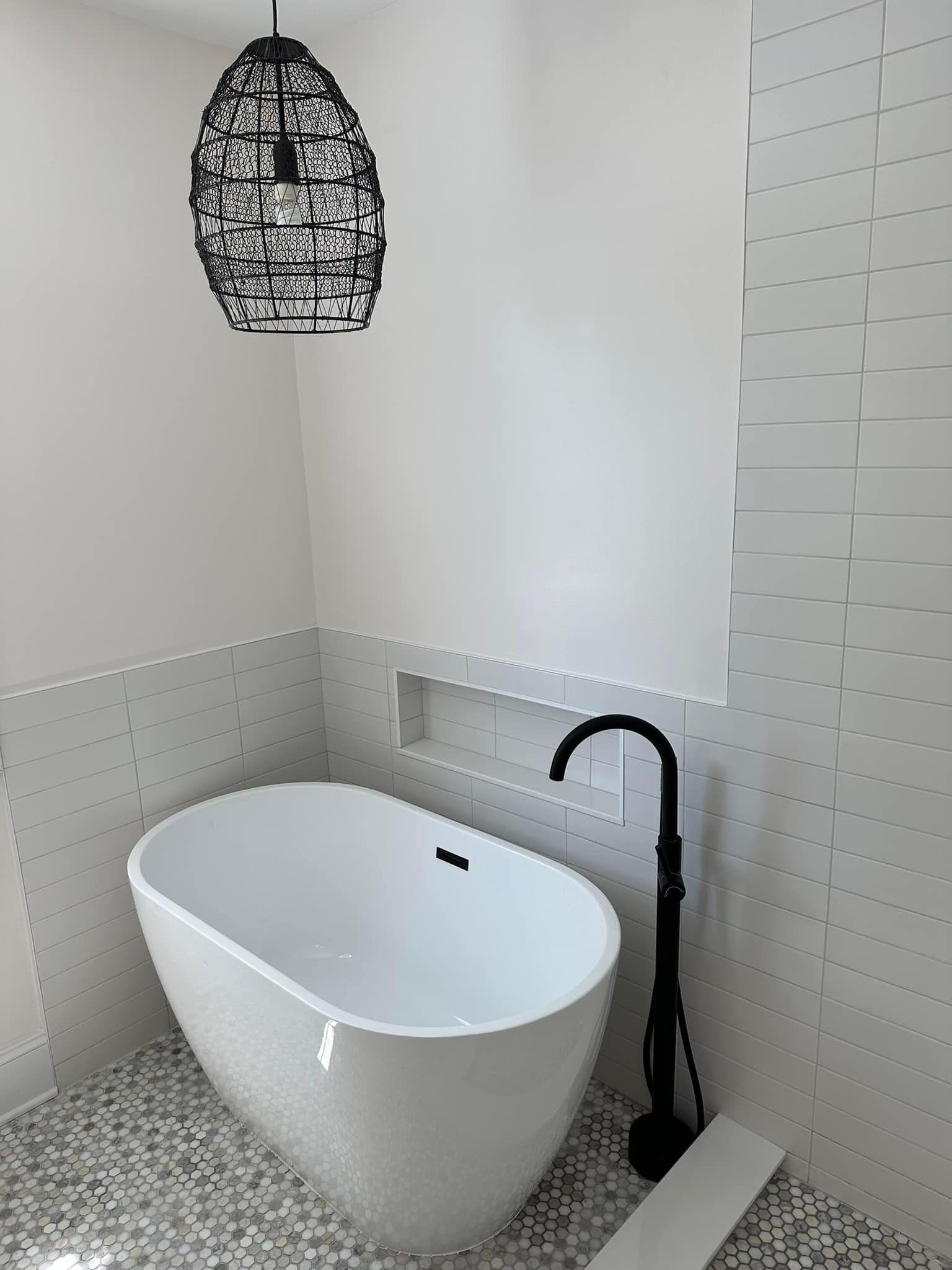 A bathroom with a white bathtub and a black faucet.