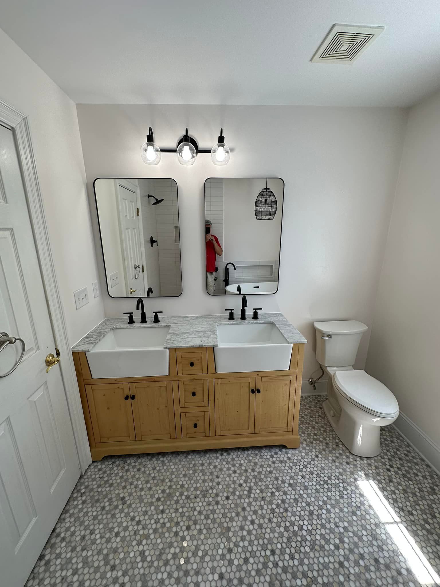 A bathroom with two sinks, a toilet, and two mirrors.