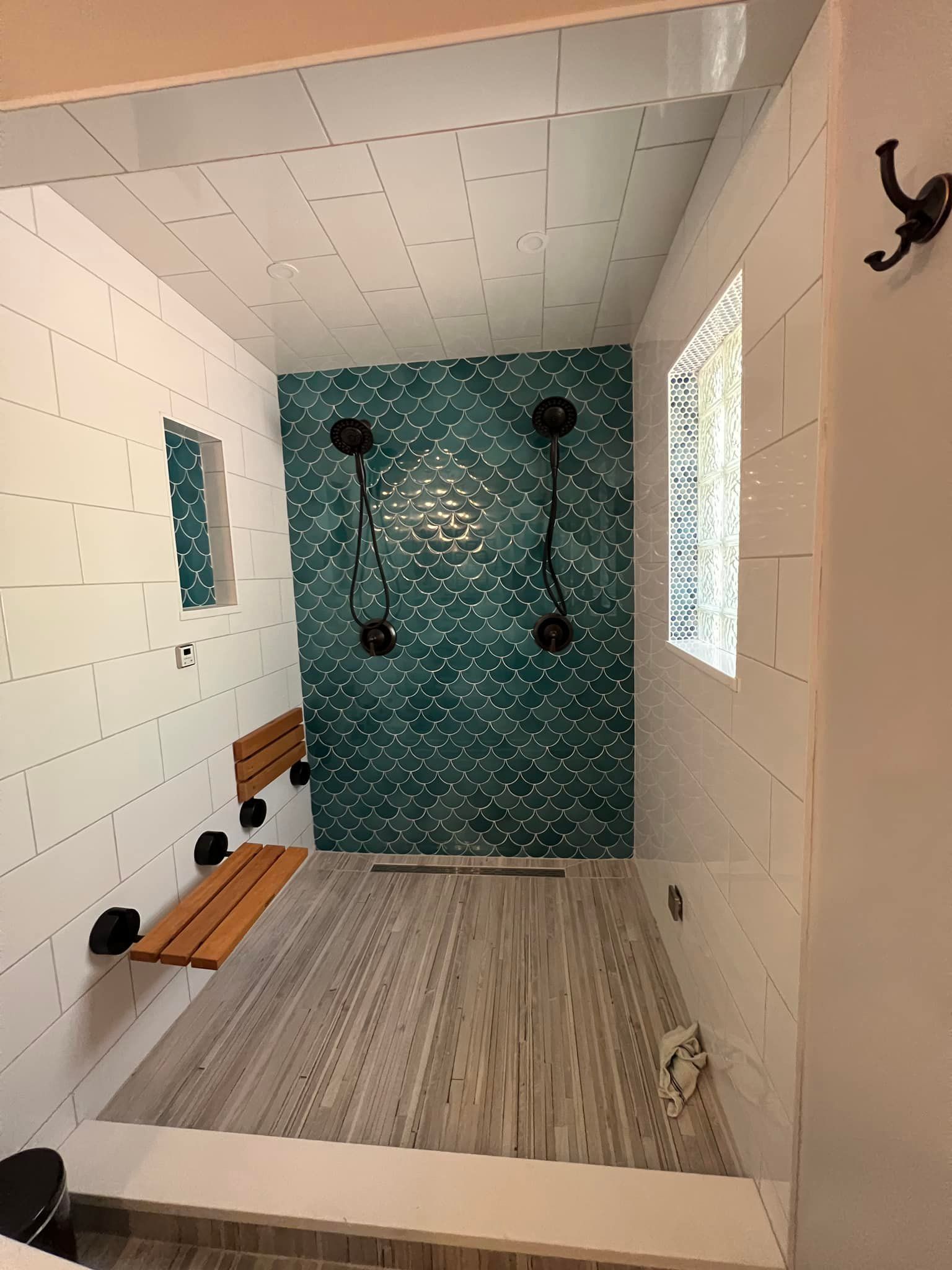 A bathroom with a blue tiled wall and a wooden bench.