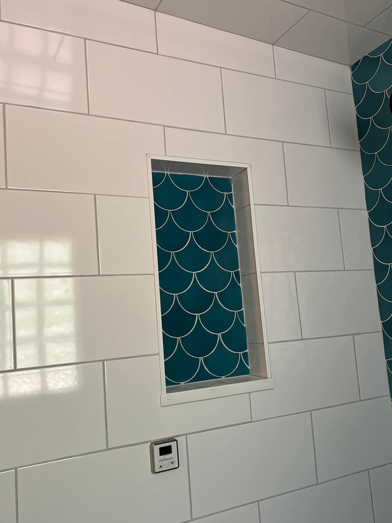 A bathroom with white tiles and a blue tile niche