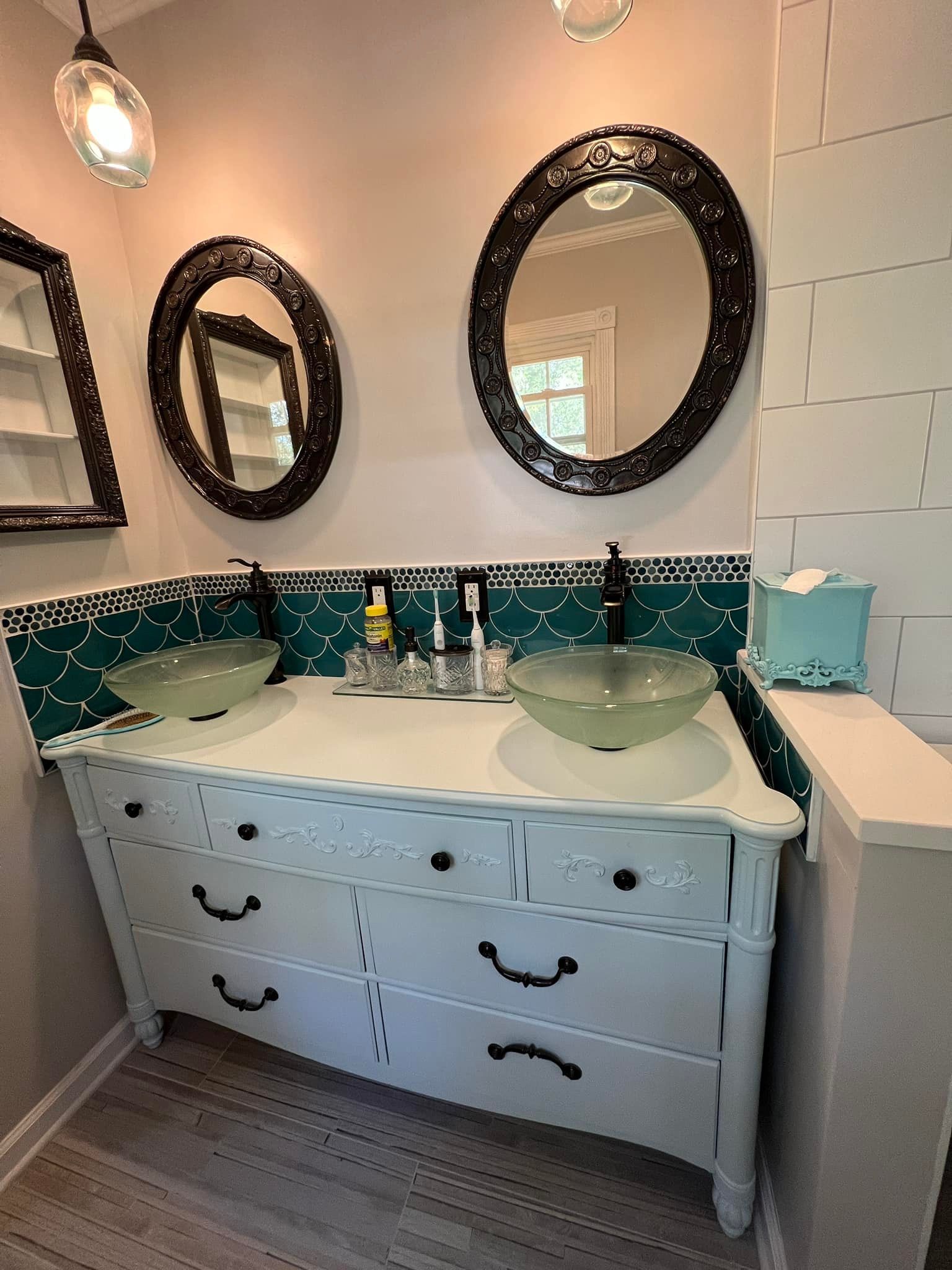 A bathroom with two sinks, two mirrors and a dresser.