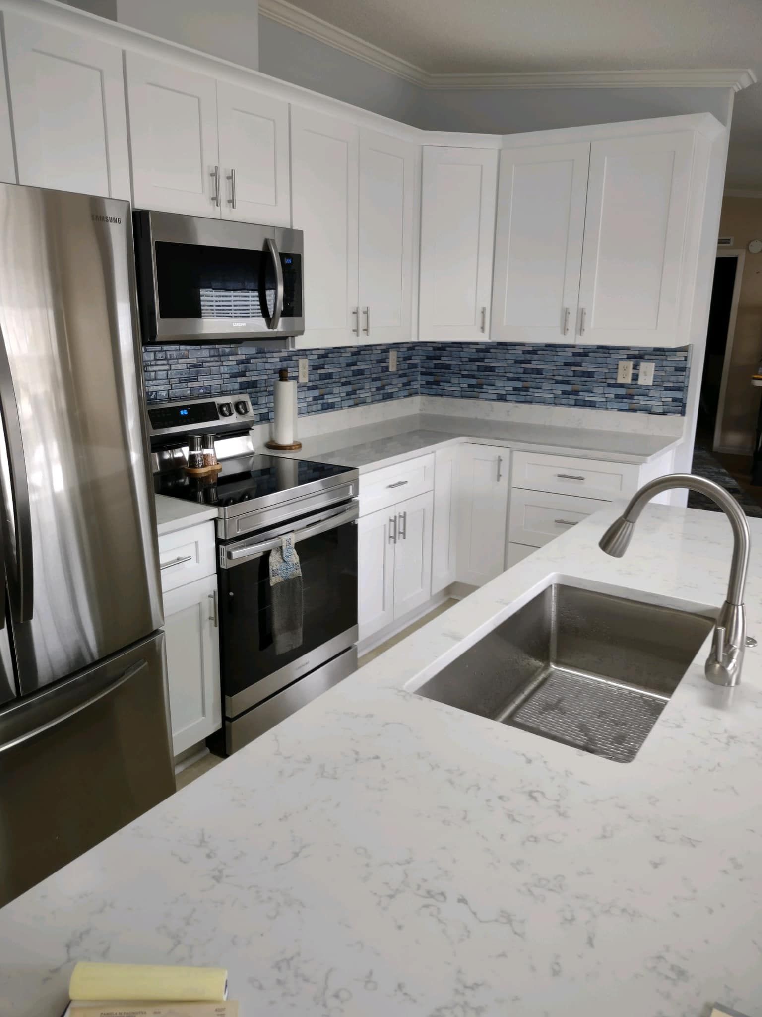 A kitchen with white cabinets, stainless steel appliances, a sink and a refrigerator.
